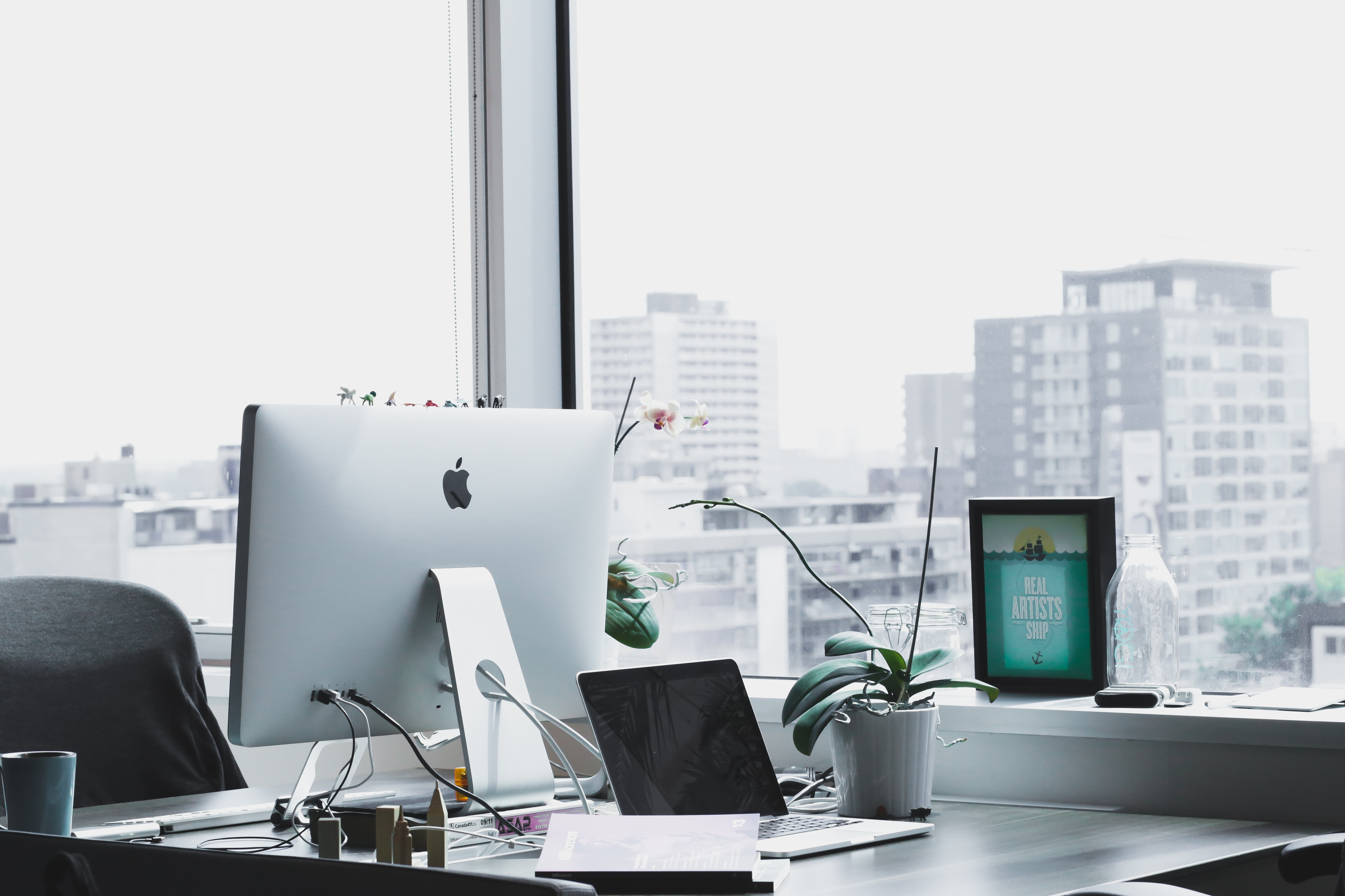 Desk with a laptop and a view of the city behind it