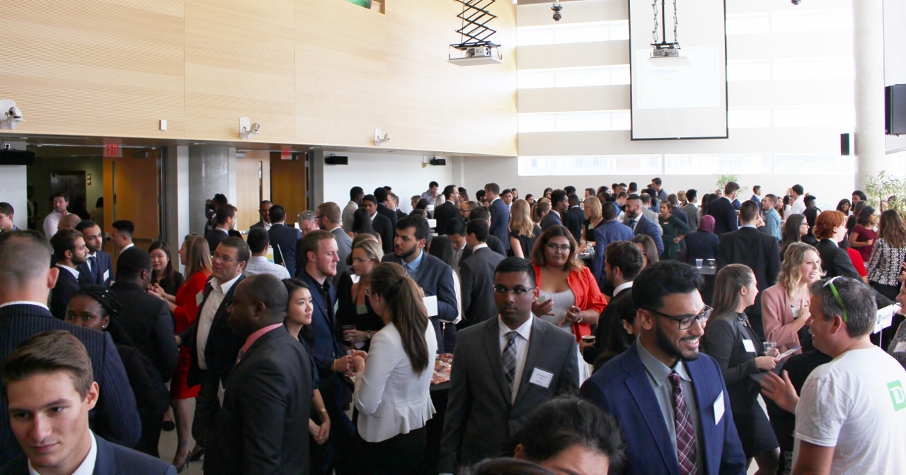 Room of professionals networking in the Desmarais building.