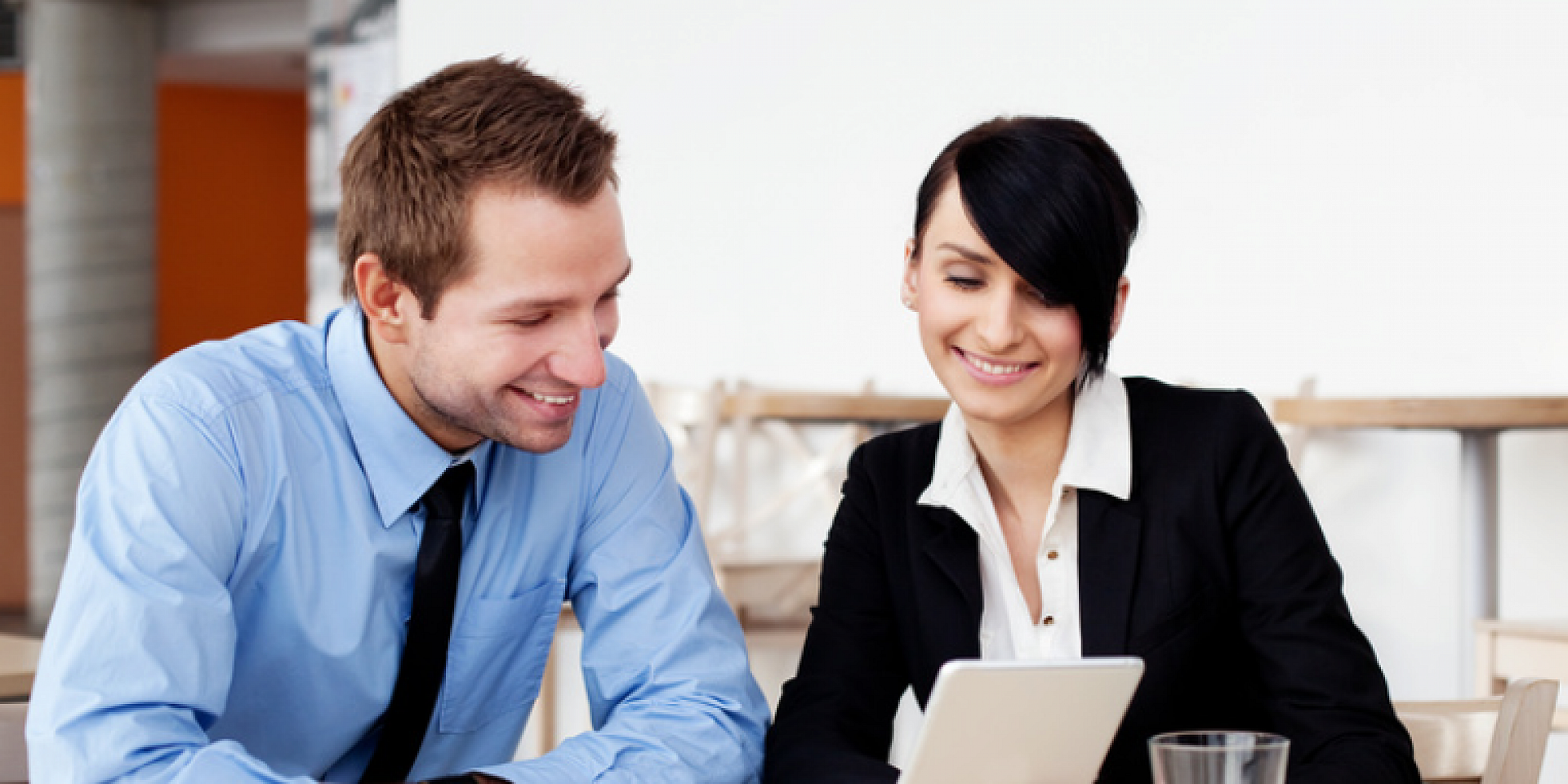 Business man and woman looking down at a laptop and smiling