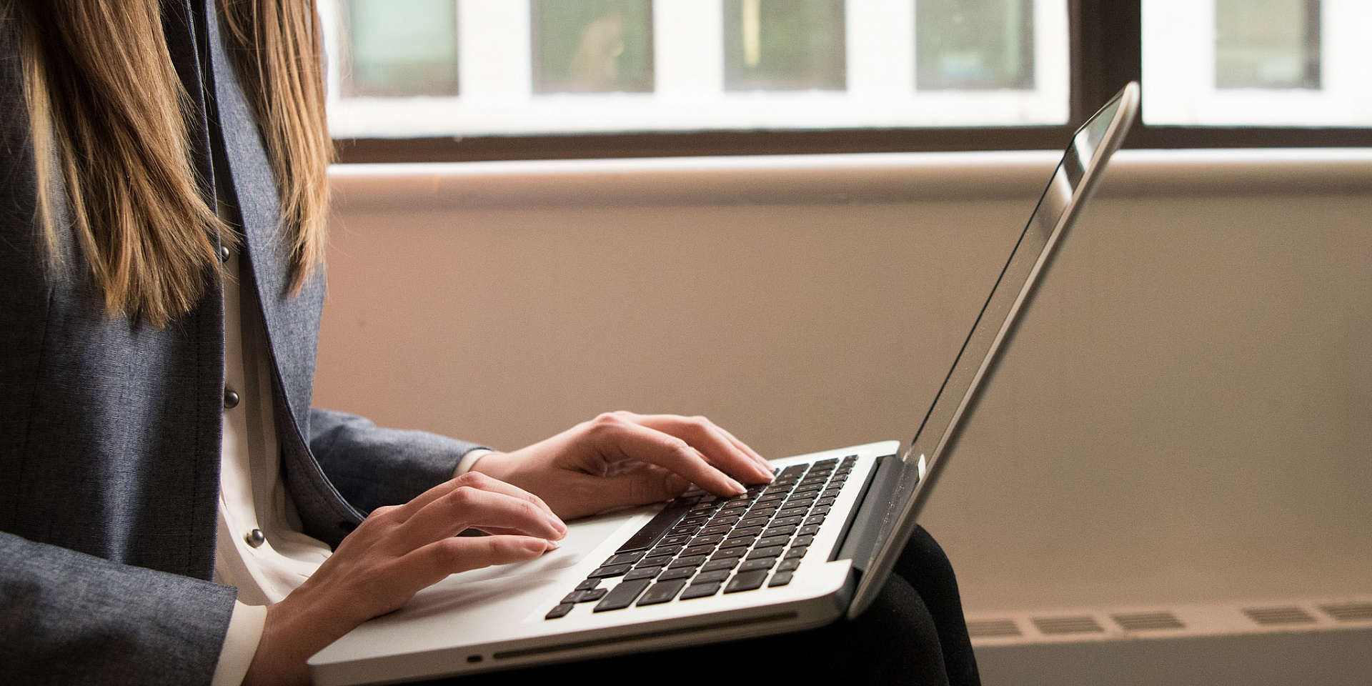 Student sitting near a window working on her laptop