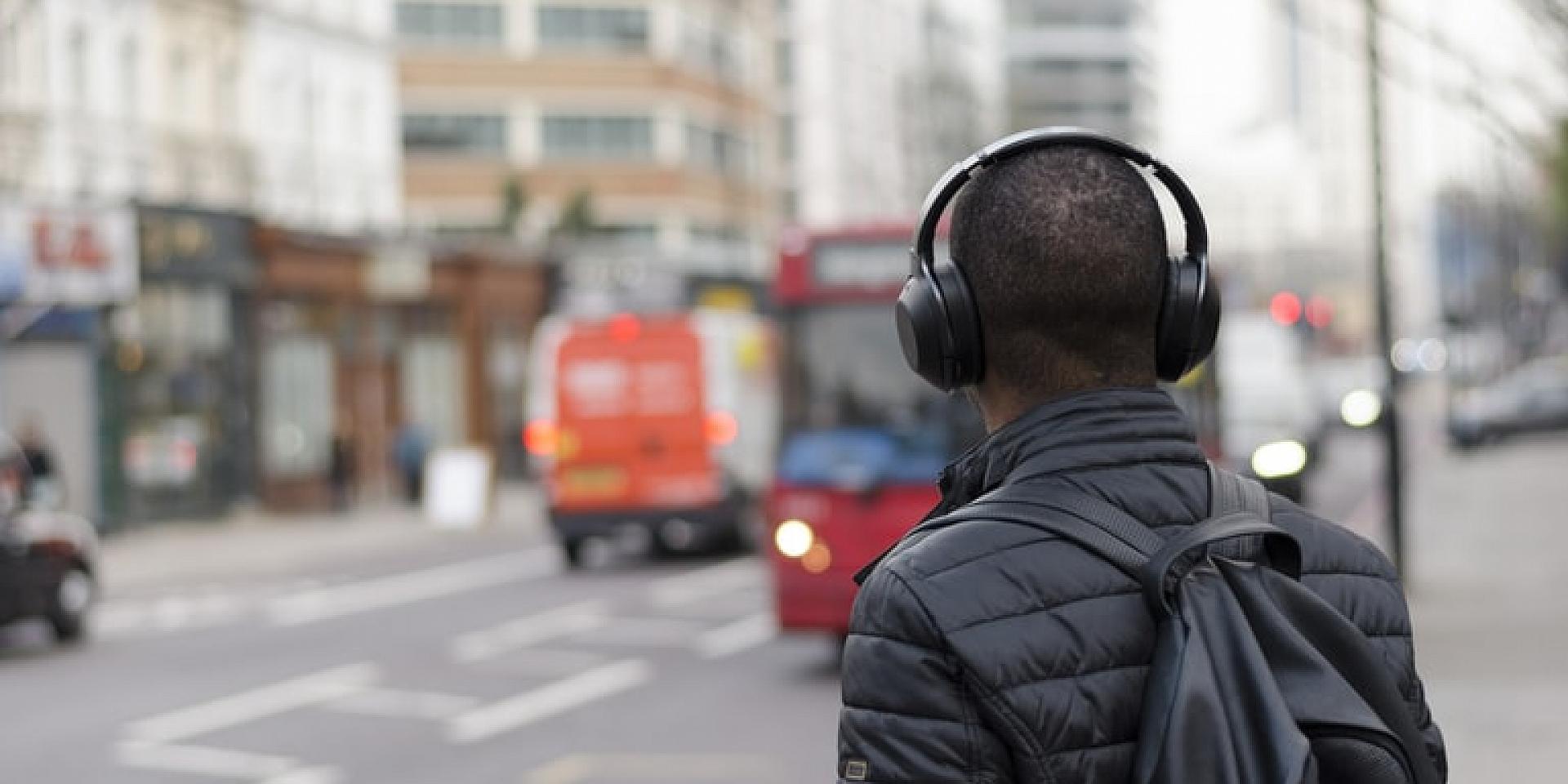 Back of man's head with headphones on, outside on the street