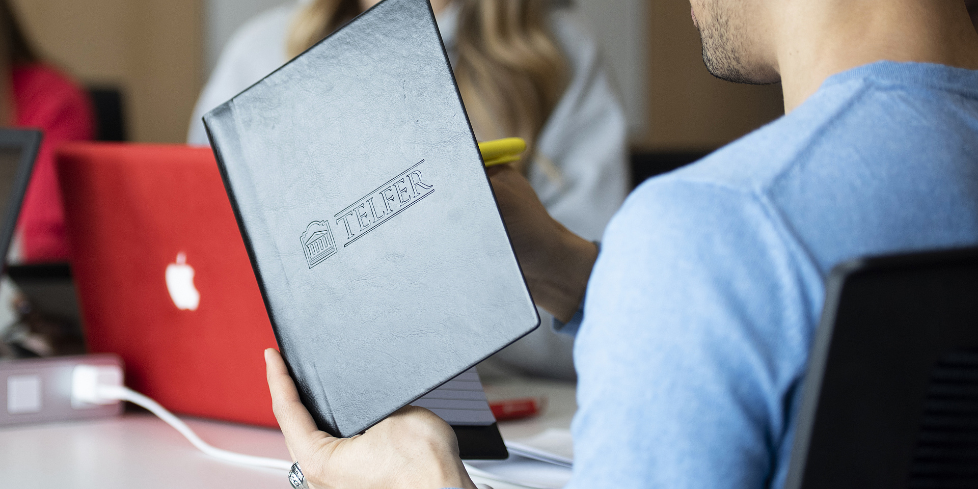 Student holding a Telfer notebook