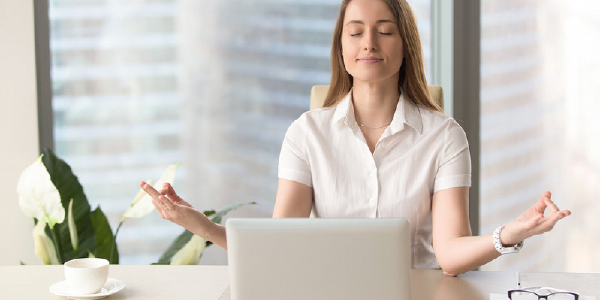 Woman meditating in front of her laptop