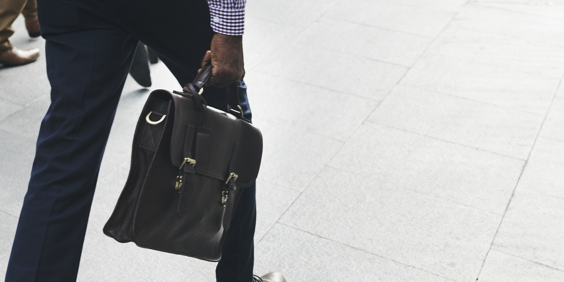 Man walking holding a messenger bag by the handle