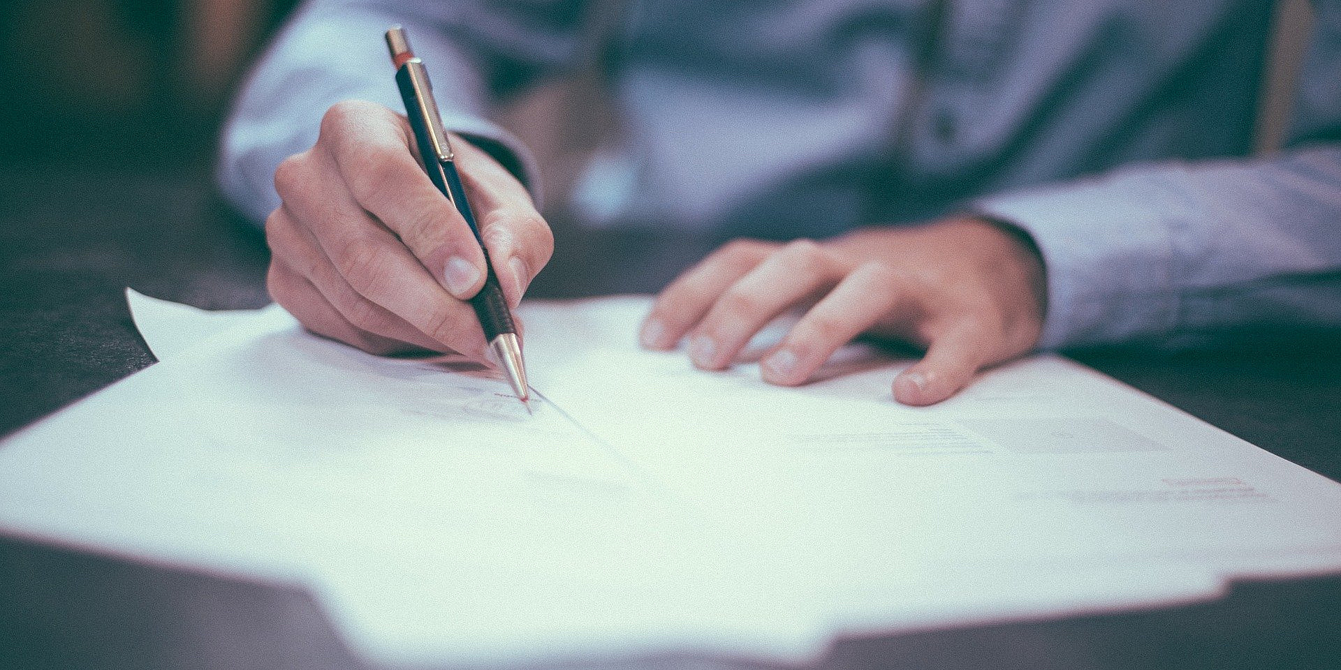 Man in a dress shirt writing with a pen