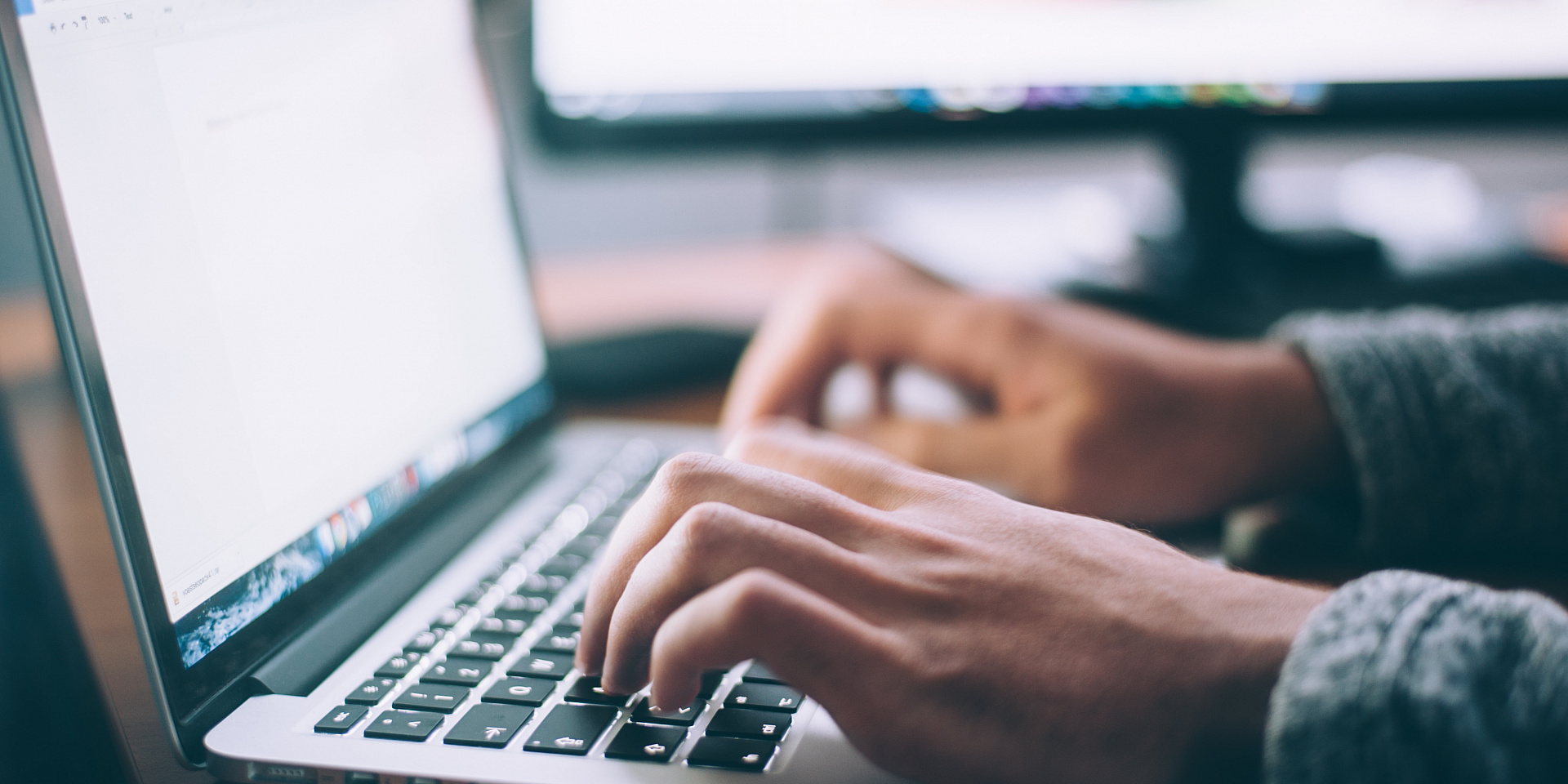 Hands typing on a laptop