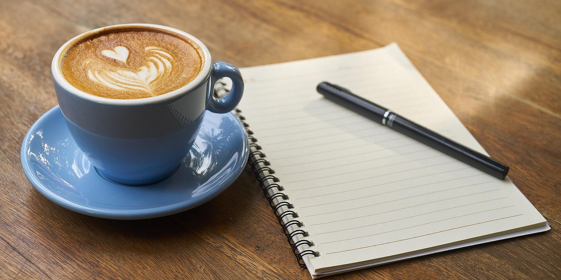 Tasse de cafe calepin de note et crayon deposé sur une table