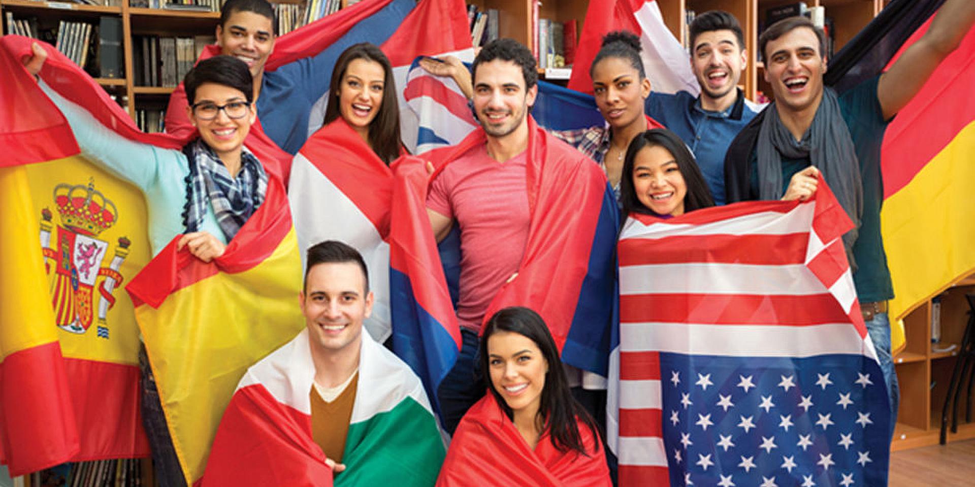 Group of students posing in a library wearing flags of different countries