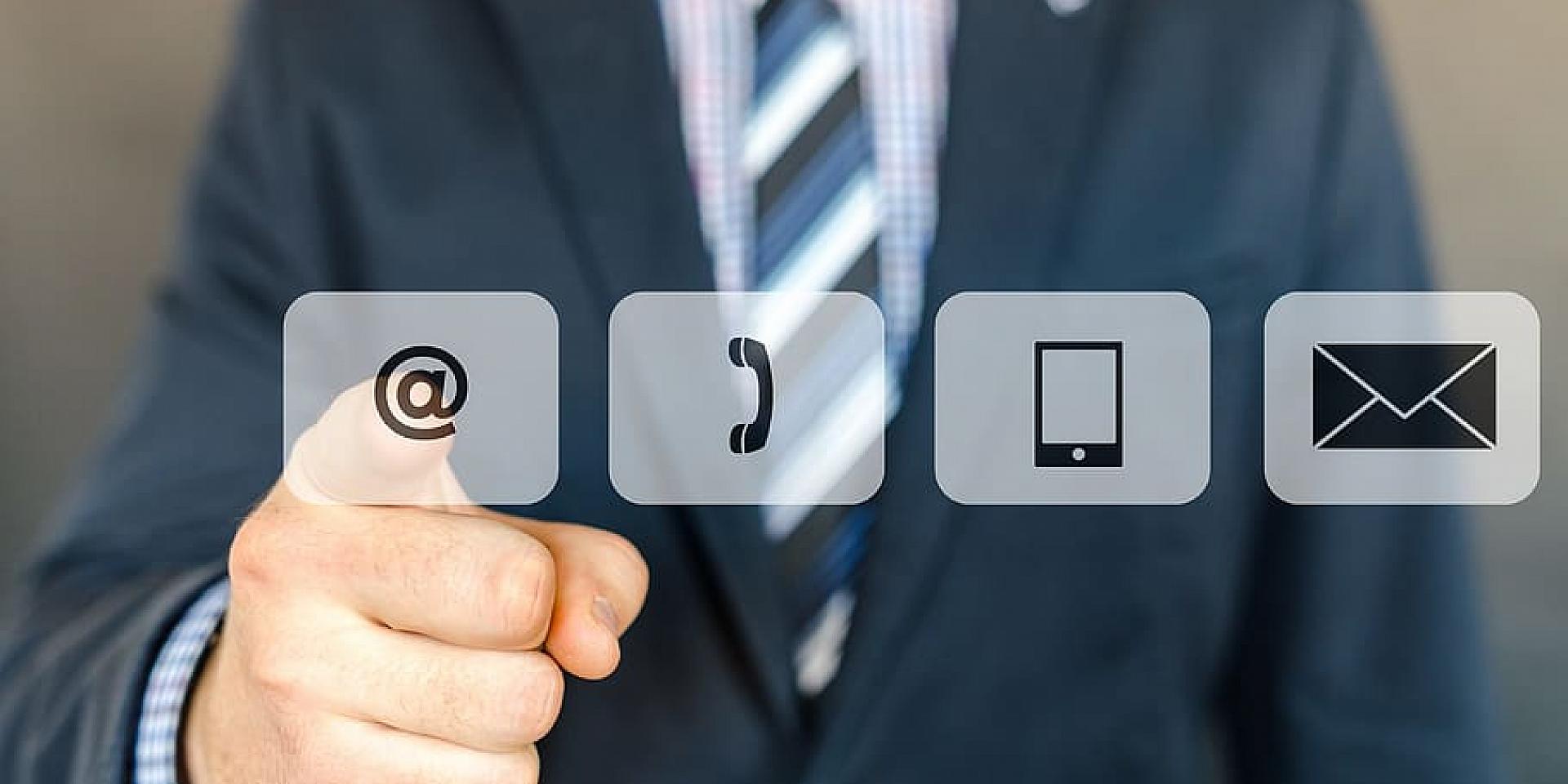 Man in a suit touching digital emojis of phone, mail and cellphone