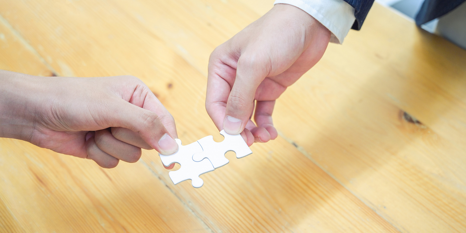 Two people each holding a piece of a puzzle together.