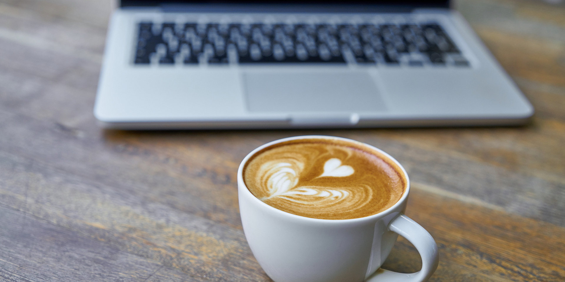 Latte art coffee on a table in front of a laptop