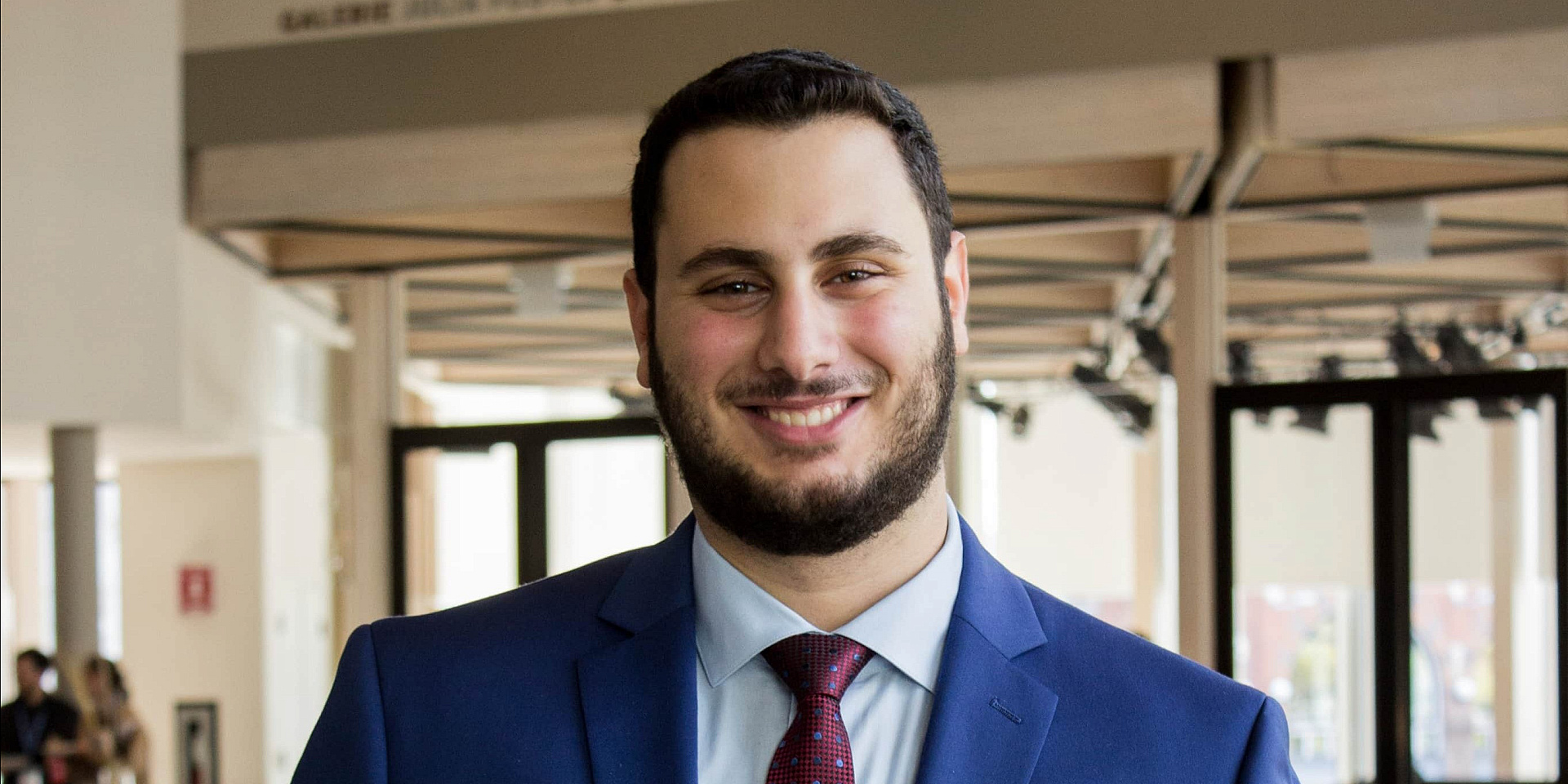 Elias wearing a blue suit and a red tie.