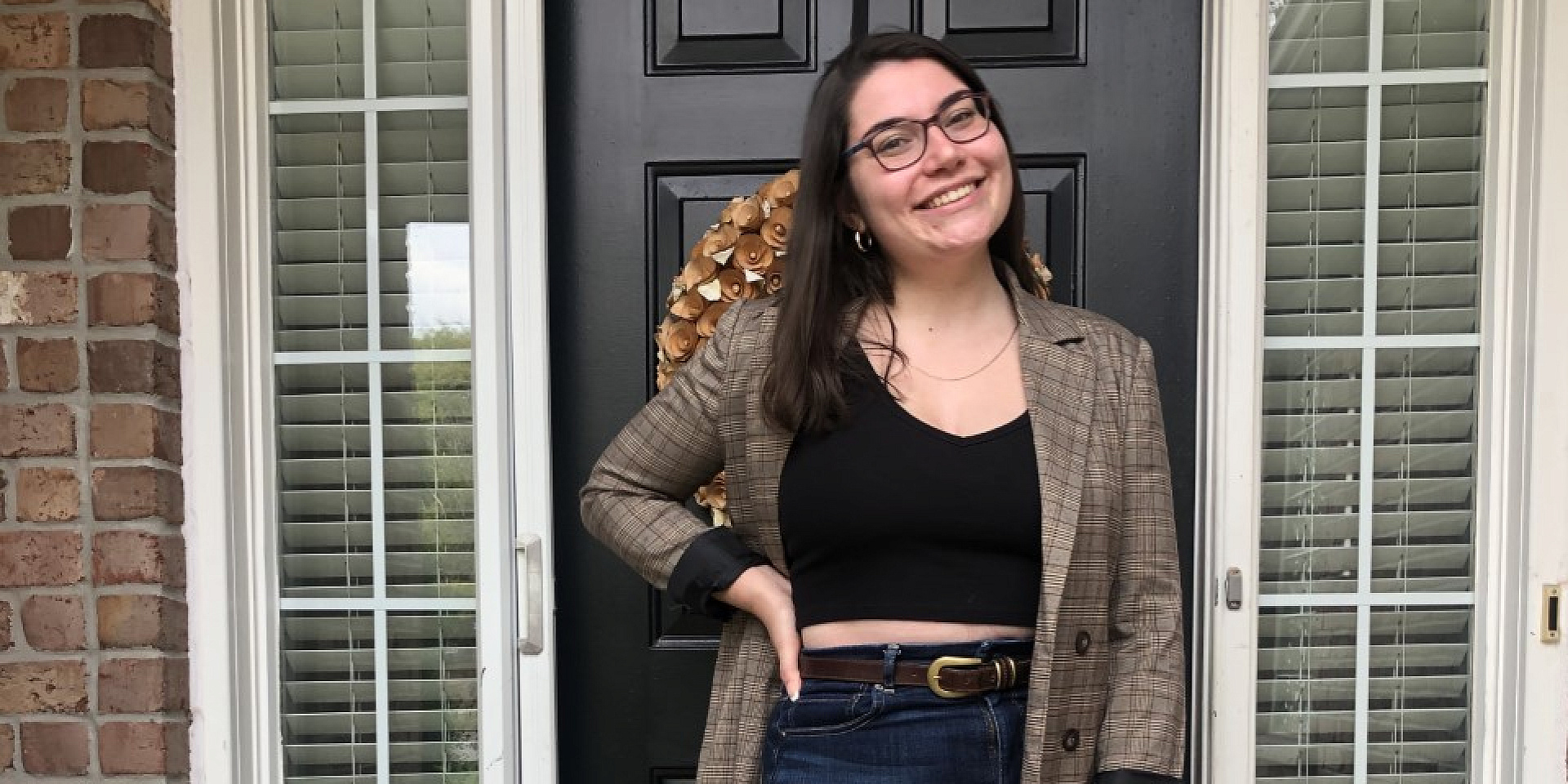 Sophia wearing a suit in front of of a house front door