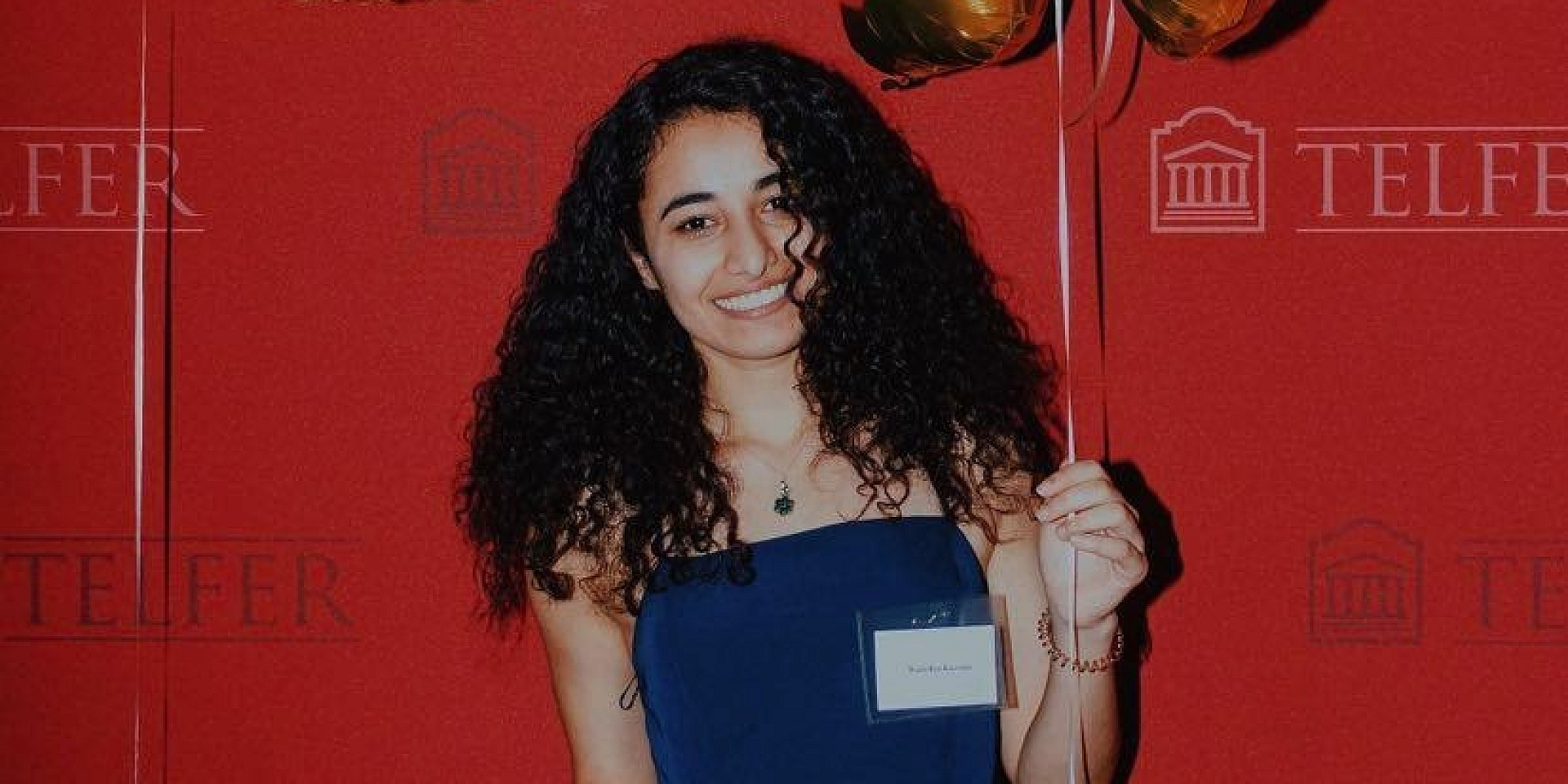 Wiam holding a balloon in front of a red Telfer background