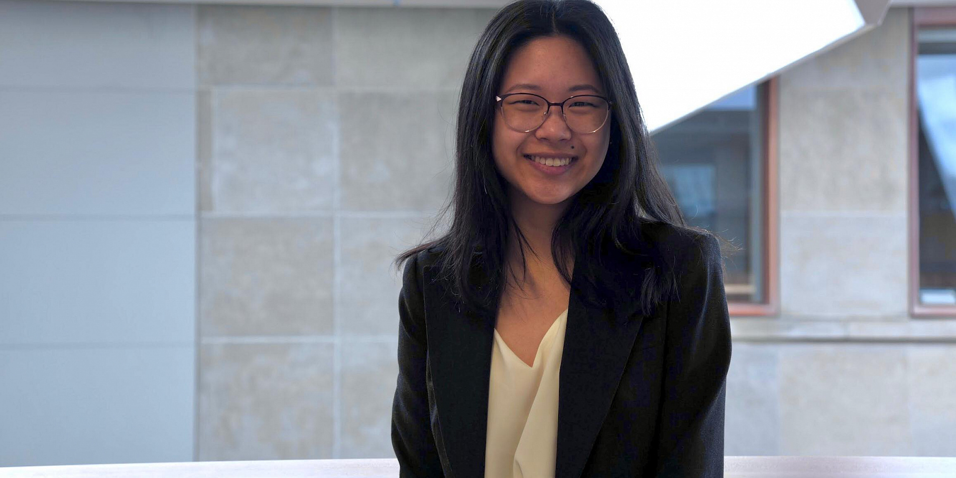 Helen wearing a suit in front of a tile wall