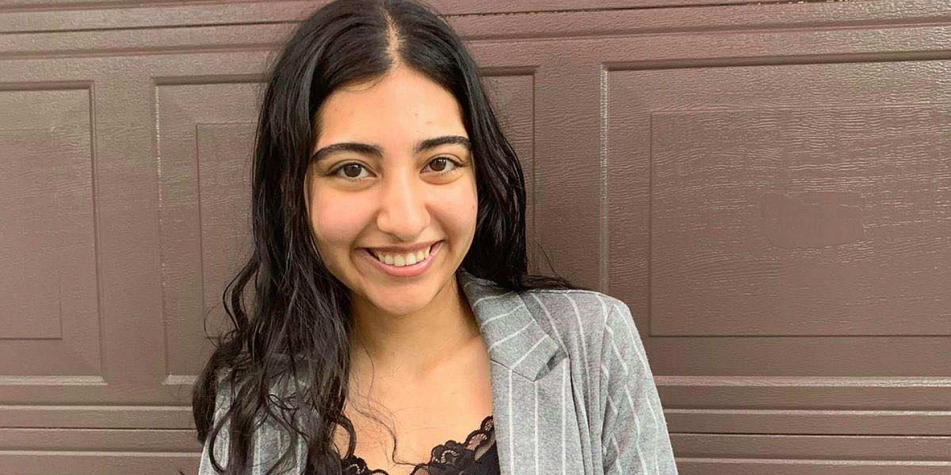 Fiona smiling in front of a brown wood wall