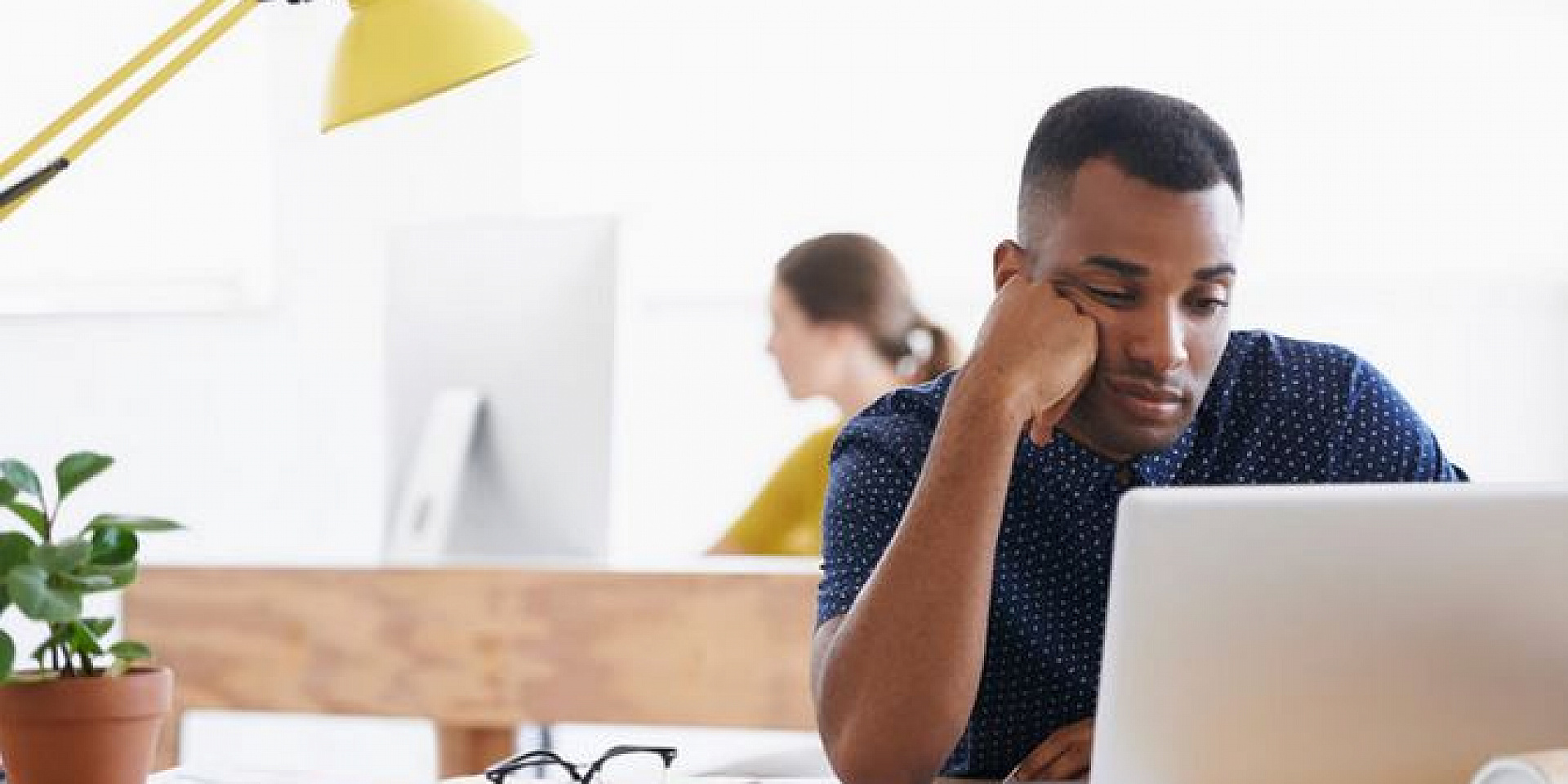 Man in a dress shirt waiting in front of his laptop.