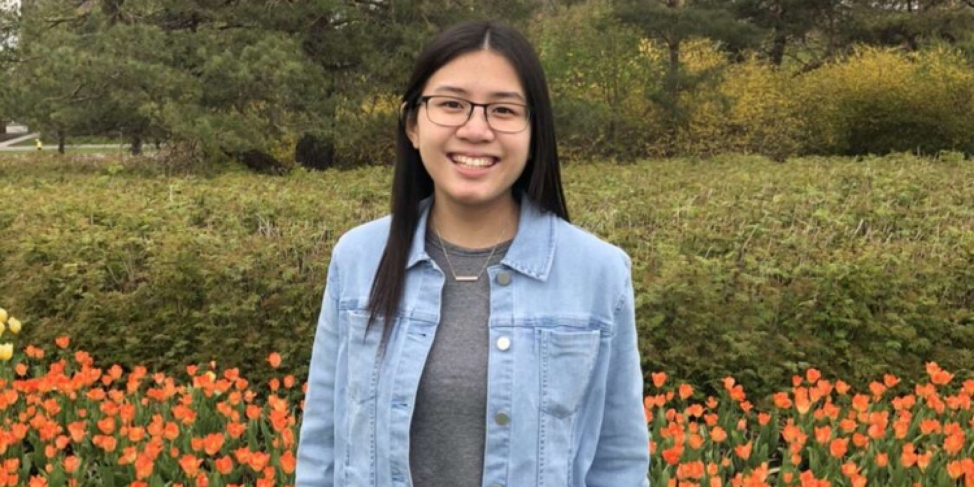 Thuy-Vi in a jean jacket in front of tulips