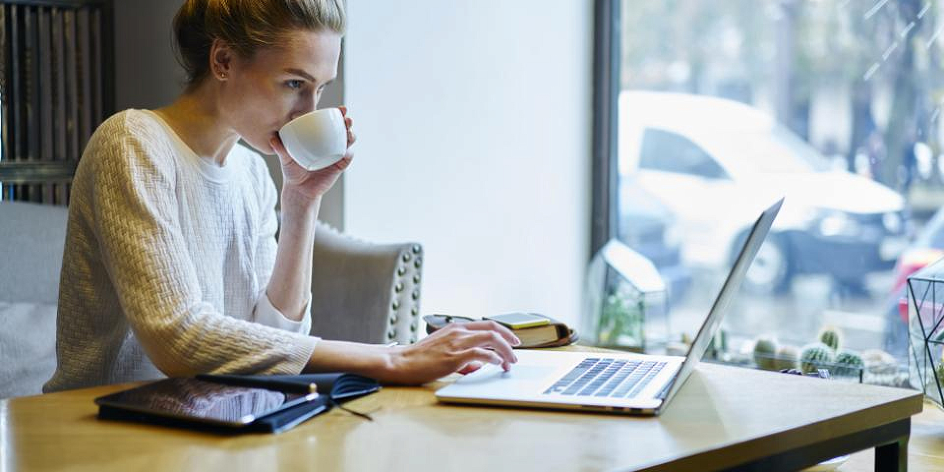 Une femme travaille sur son laptop en buvant un café