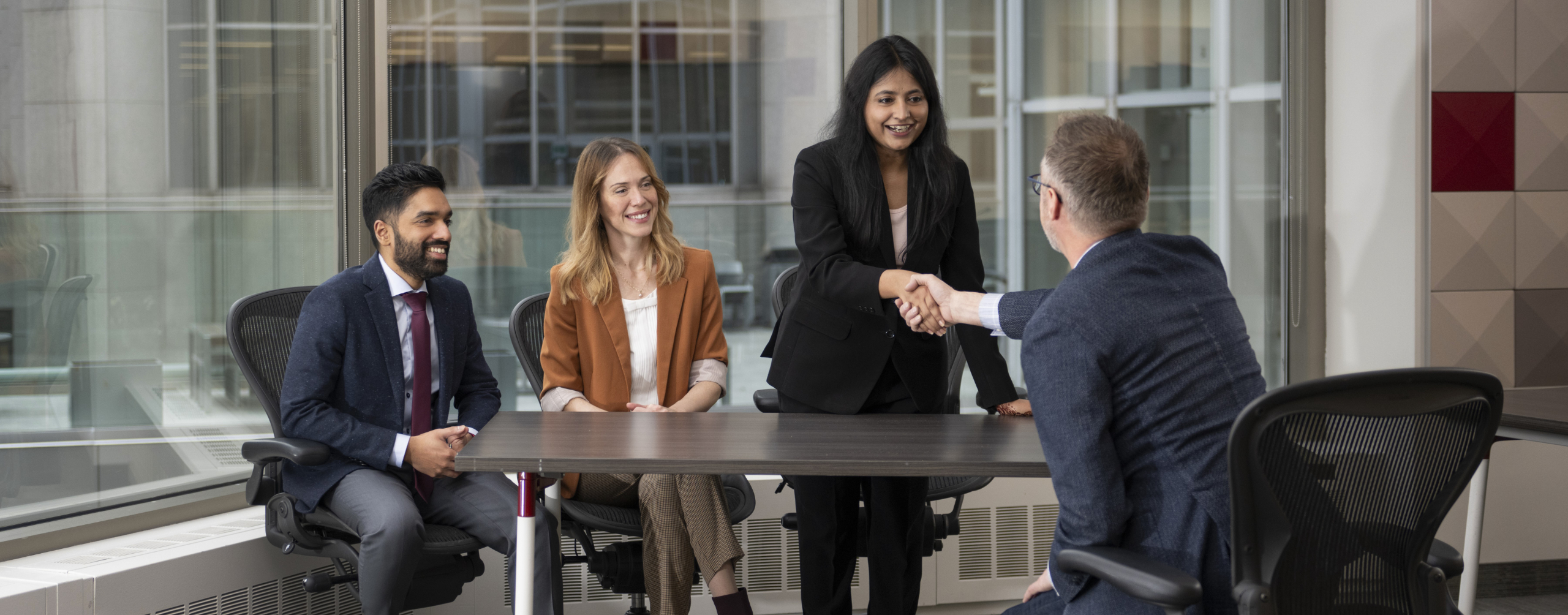 multiple person sitting at at table chatting and shaking hands