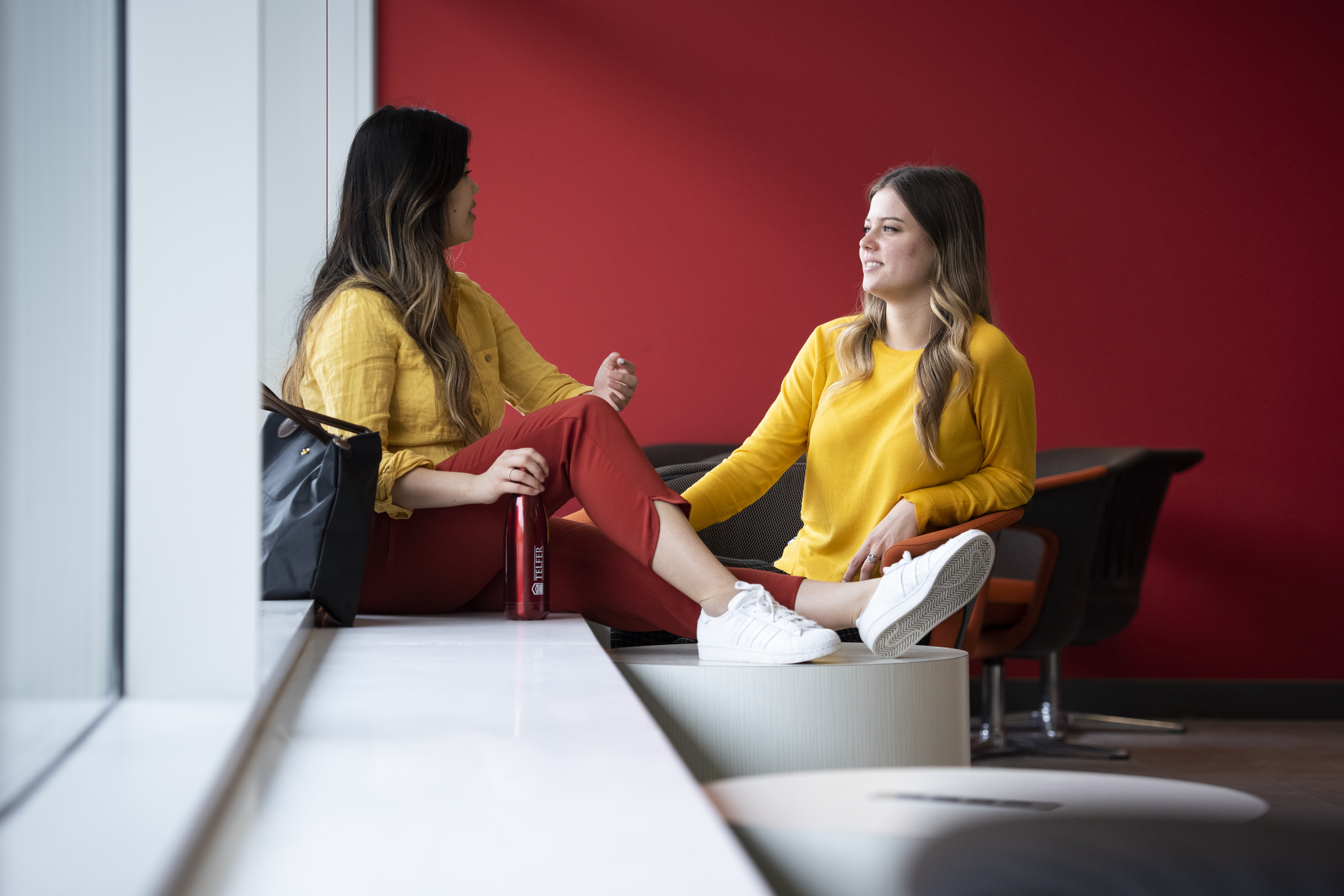 2 girls sitting and chatting in a study space on campus