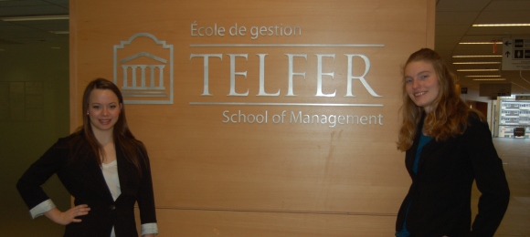Andrea Kuntz et Jennifer Proulx devant le logo de l'École Telfer dans le pavillon Desmarais