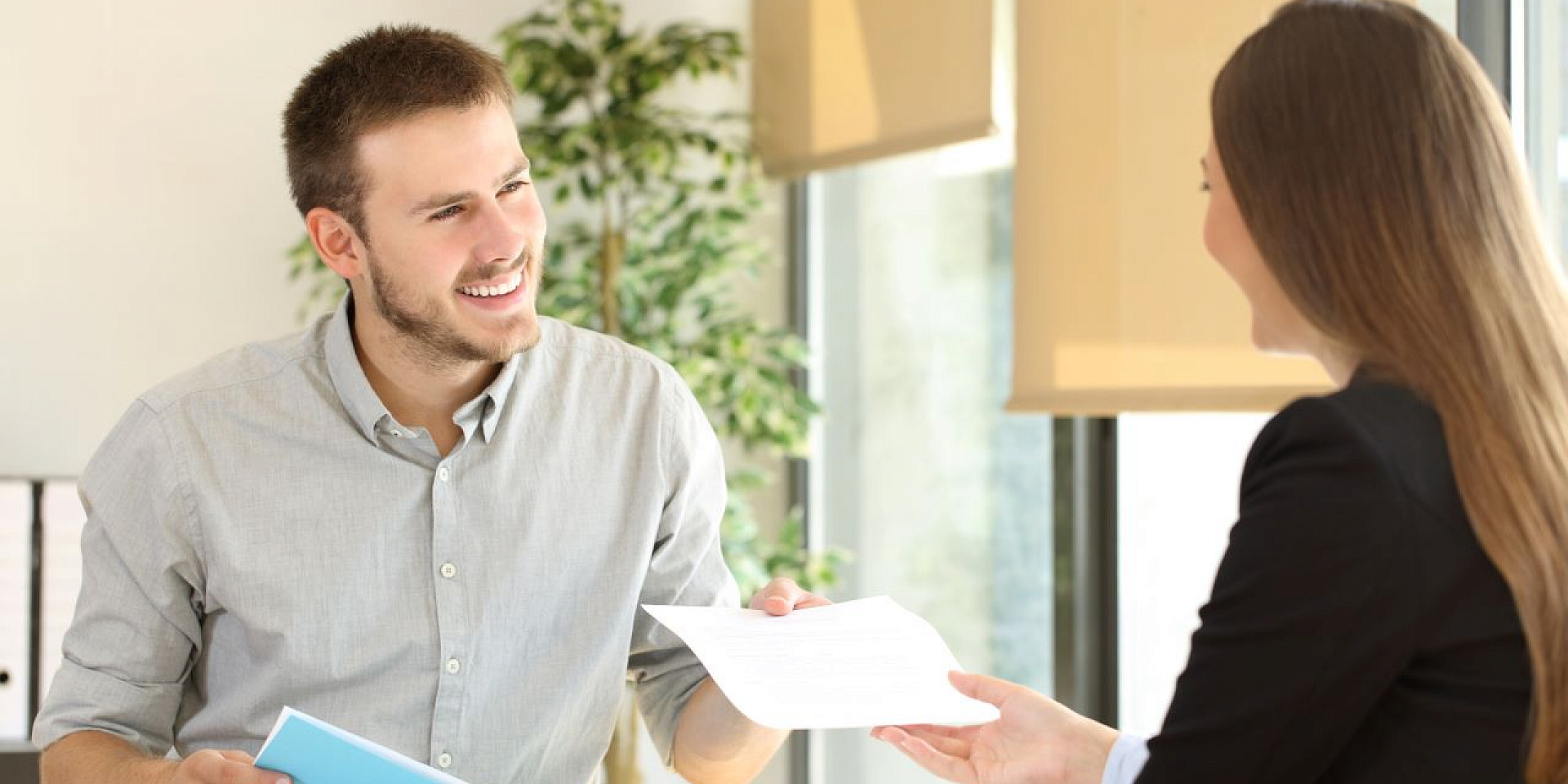 Man handing over his CV to a woman.