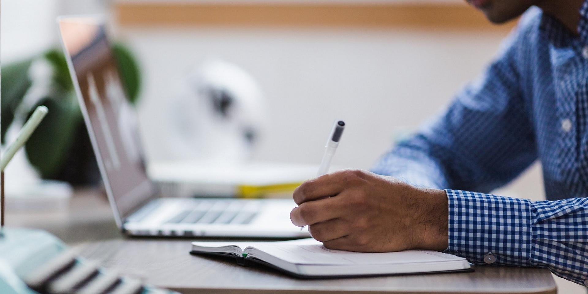 man writing on notepad