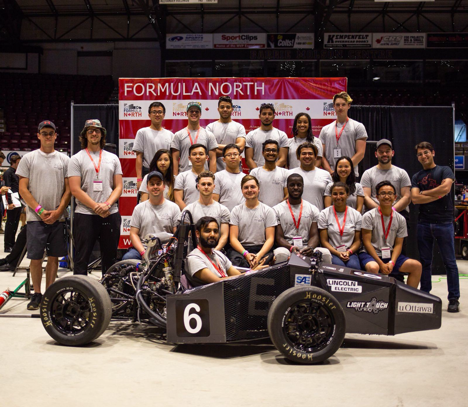 A group of students from Formula uOttawa sitting with their constructed car