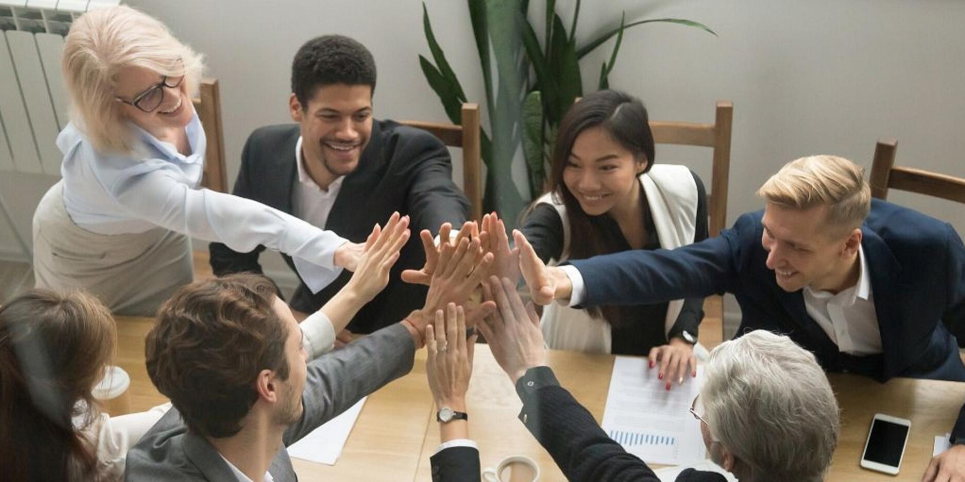 Employees at work reaching in to give eachother a high-five.