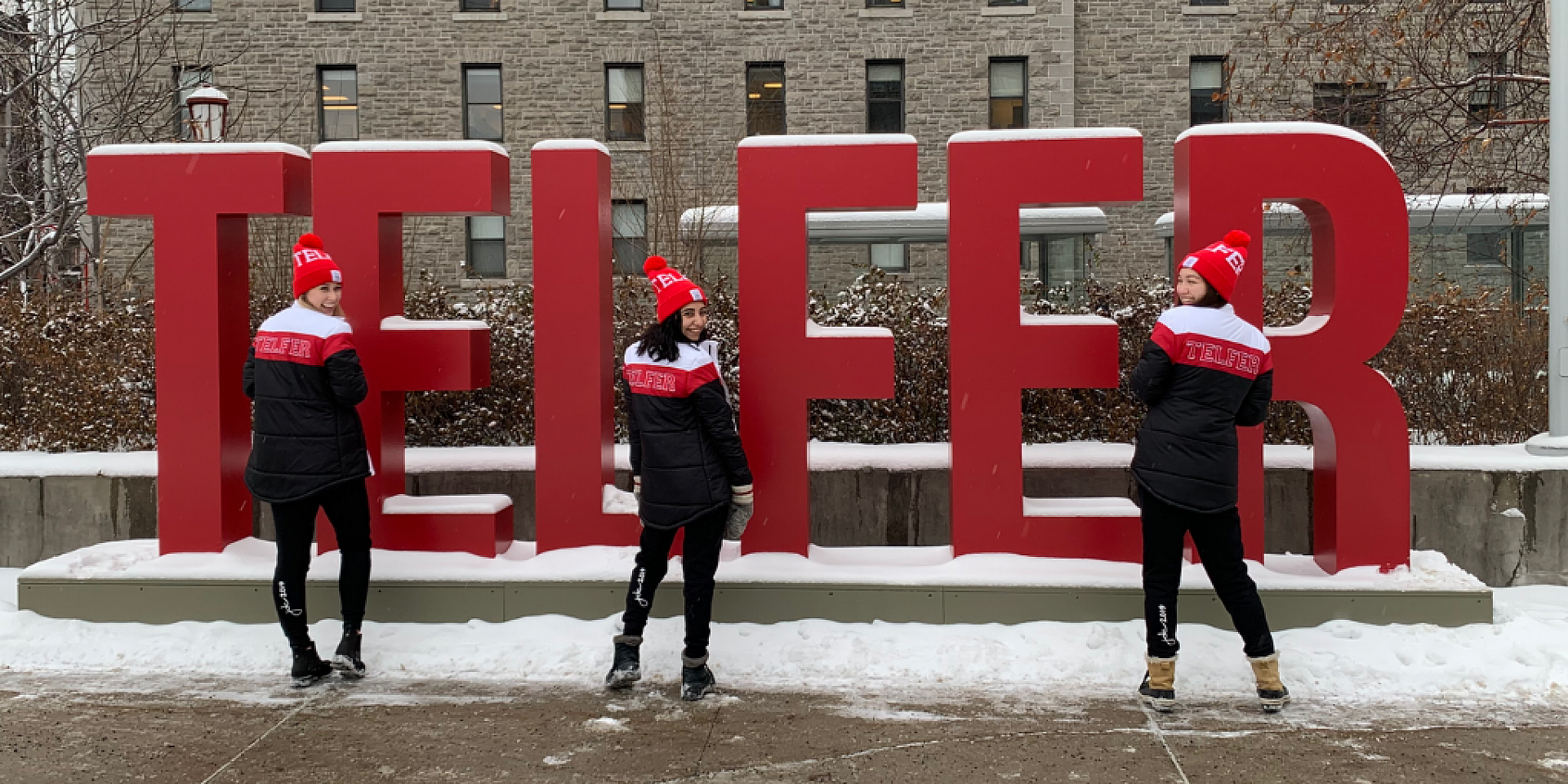 three students smiling in front of the telfer sign