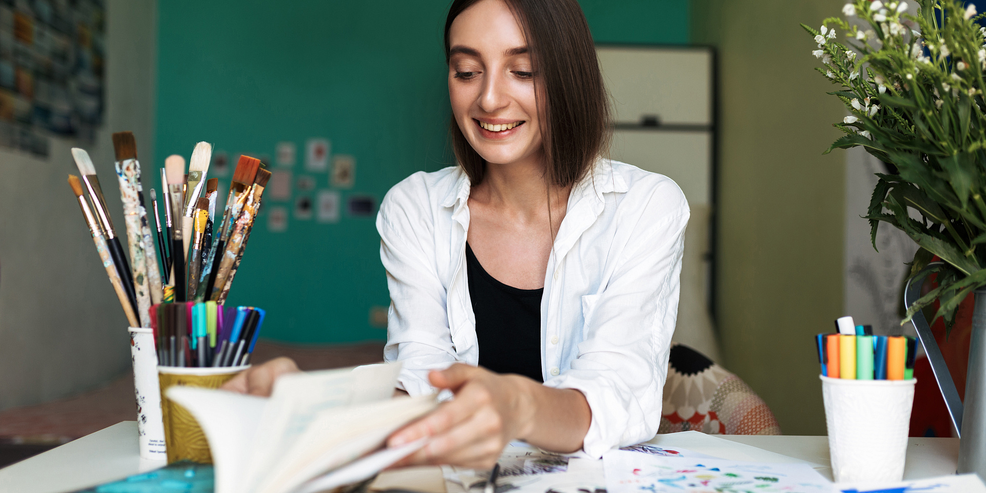 Jeune femme souriante assise à un bureau en train de peinturer