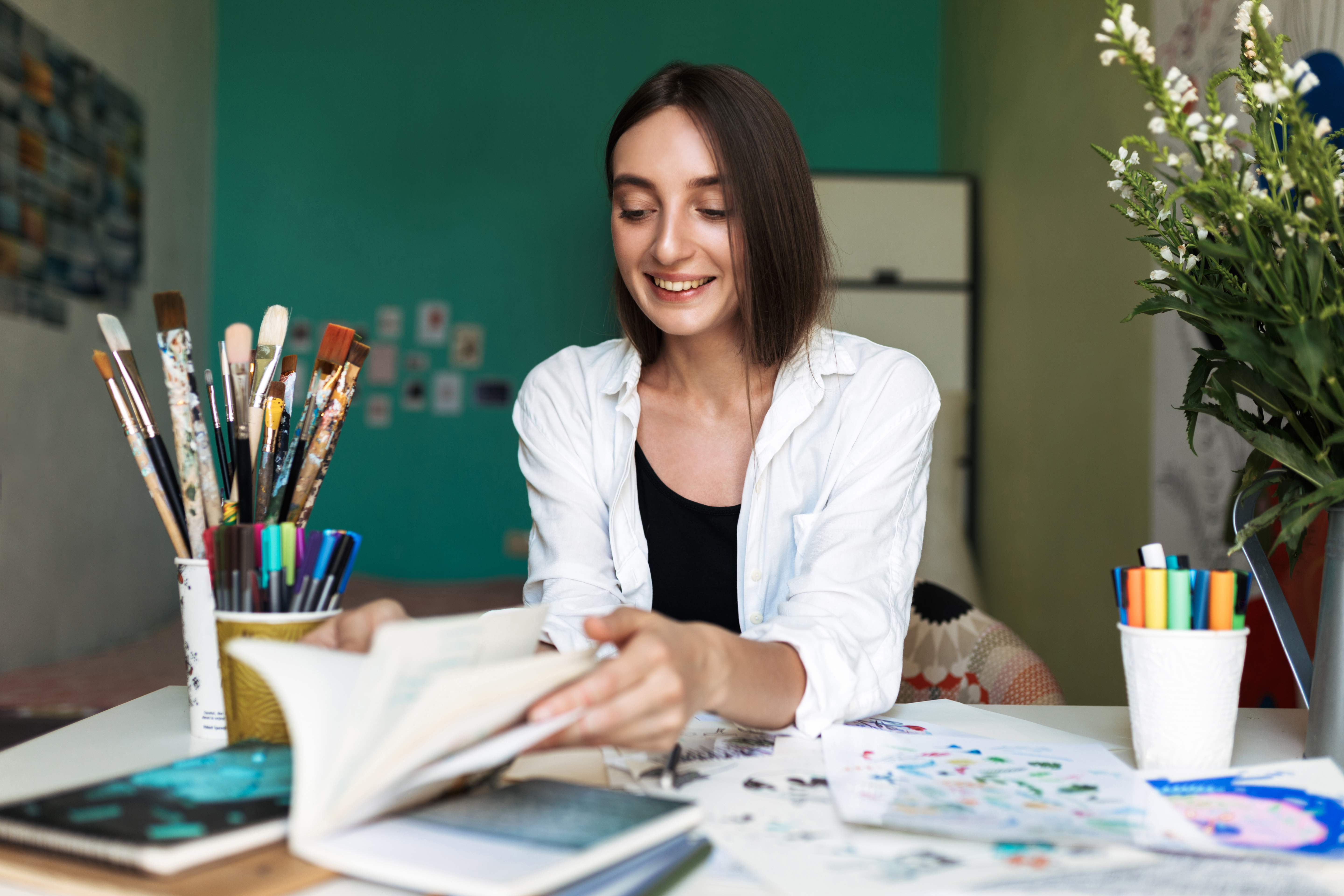 Jeune femme souriante assise à un bureau en train de peinturer