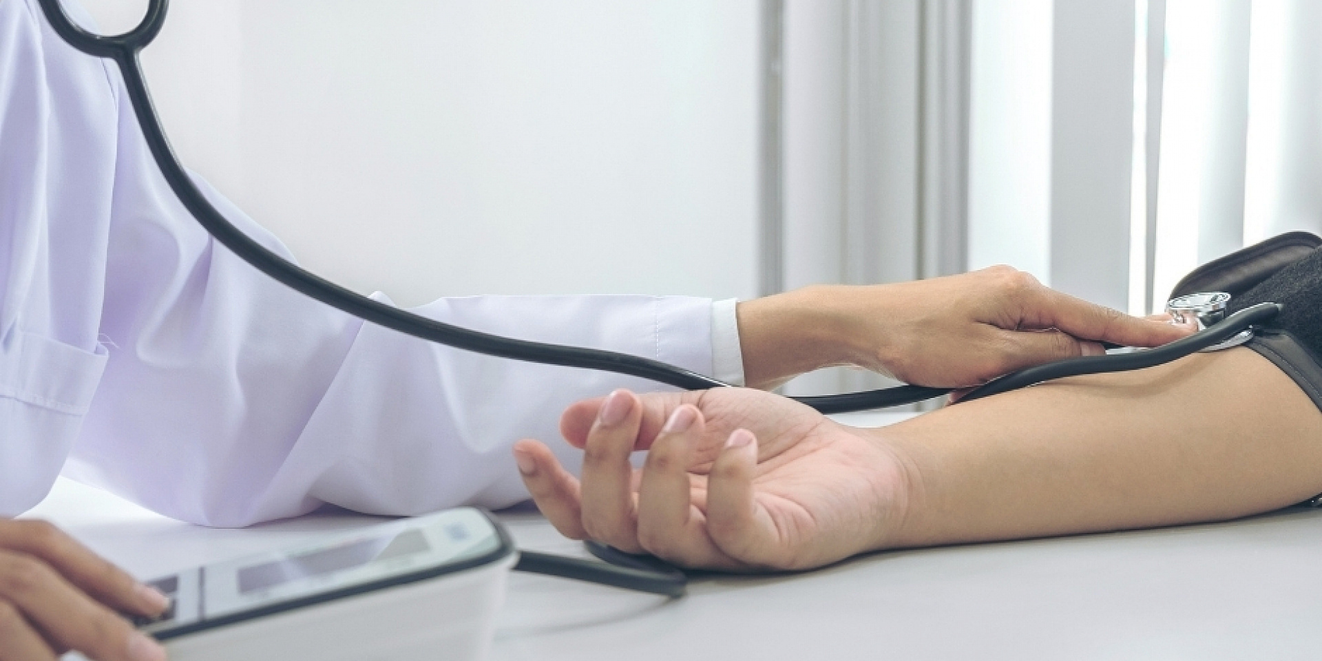 Doctor taking the pulse of a patient using a stethoscope