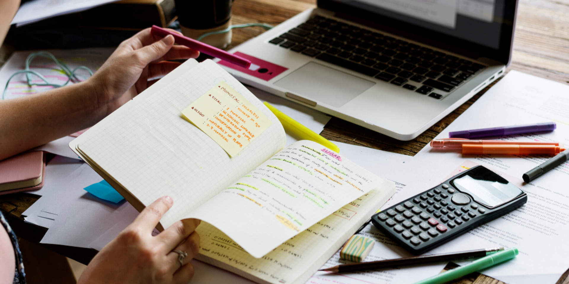 Student studying at home with notebook, laptop, and calculator