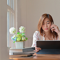 female college student working from home with cellphone and tablet