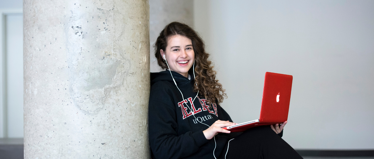 Un étudiant souriant et assis avec un laptop et des écouteurs