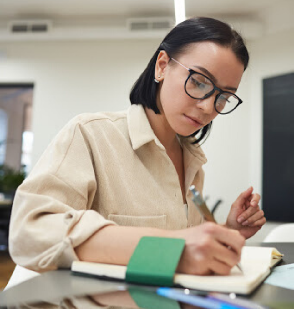 une étudiante écrivant des notes dans un cahier de notes