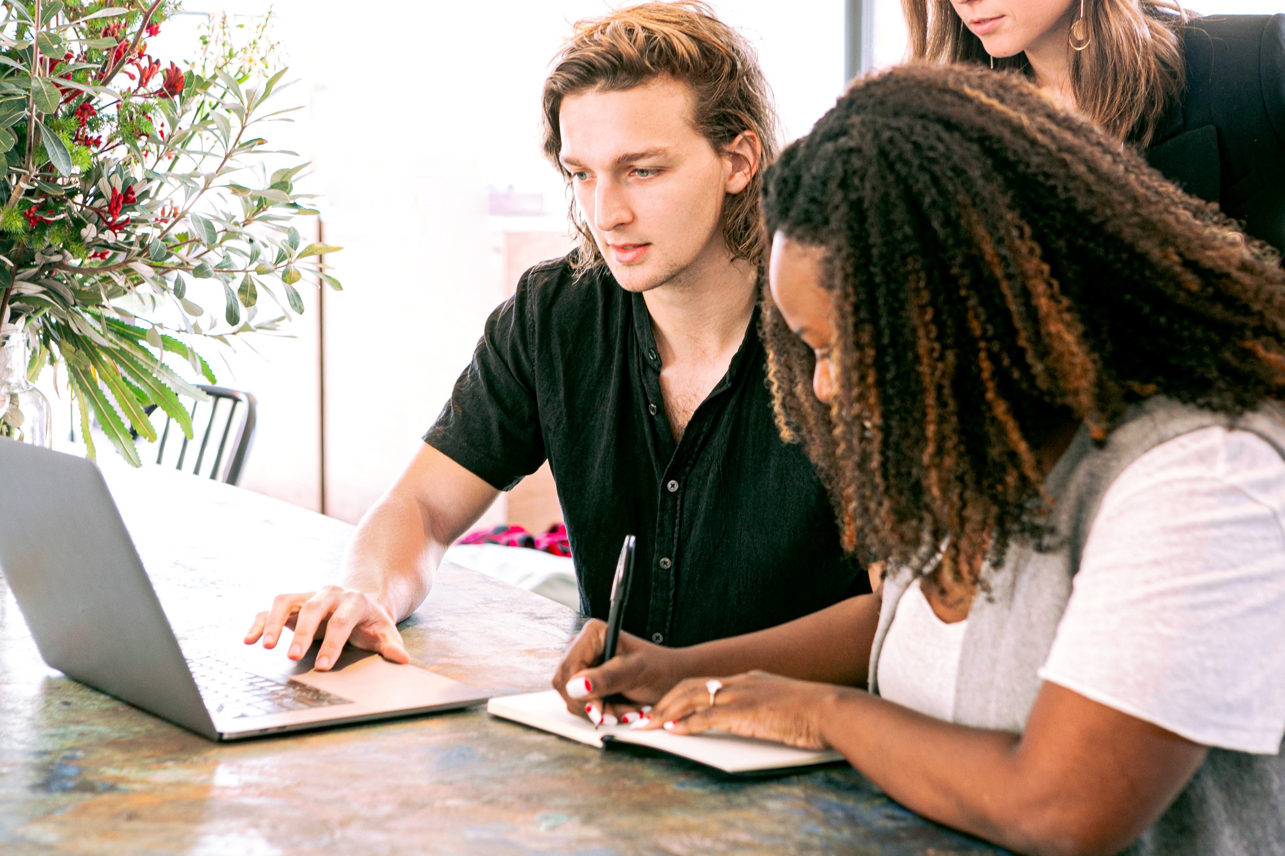 three students looking at notes and a laptop