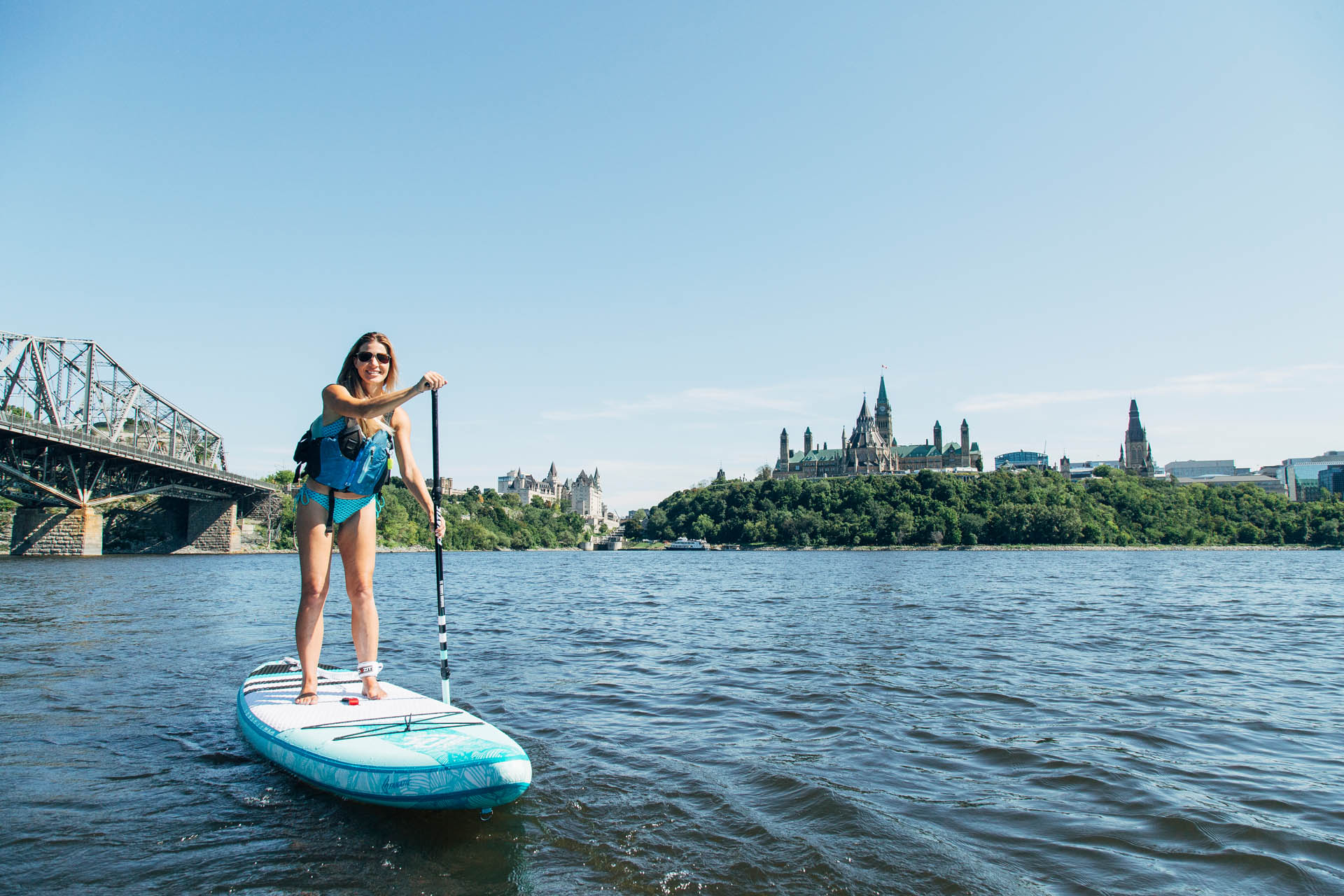 Woman on a stand up paddle board on the Ottawa River in front of Canada's Parliamant