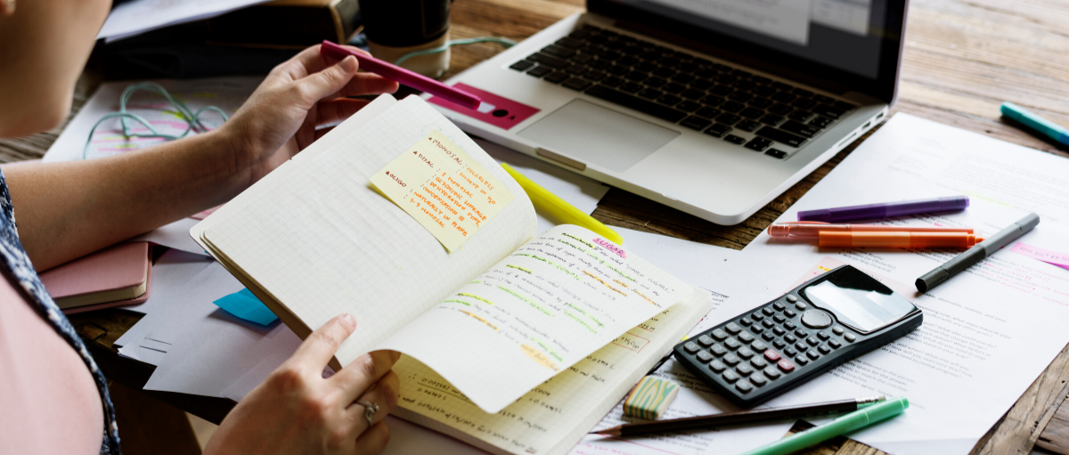Student studying at home with notebook, laptop, and calculator