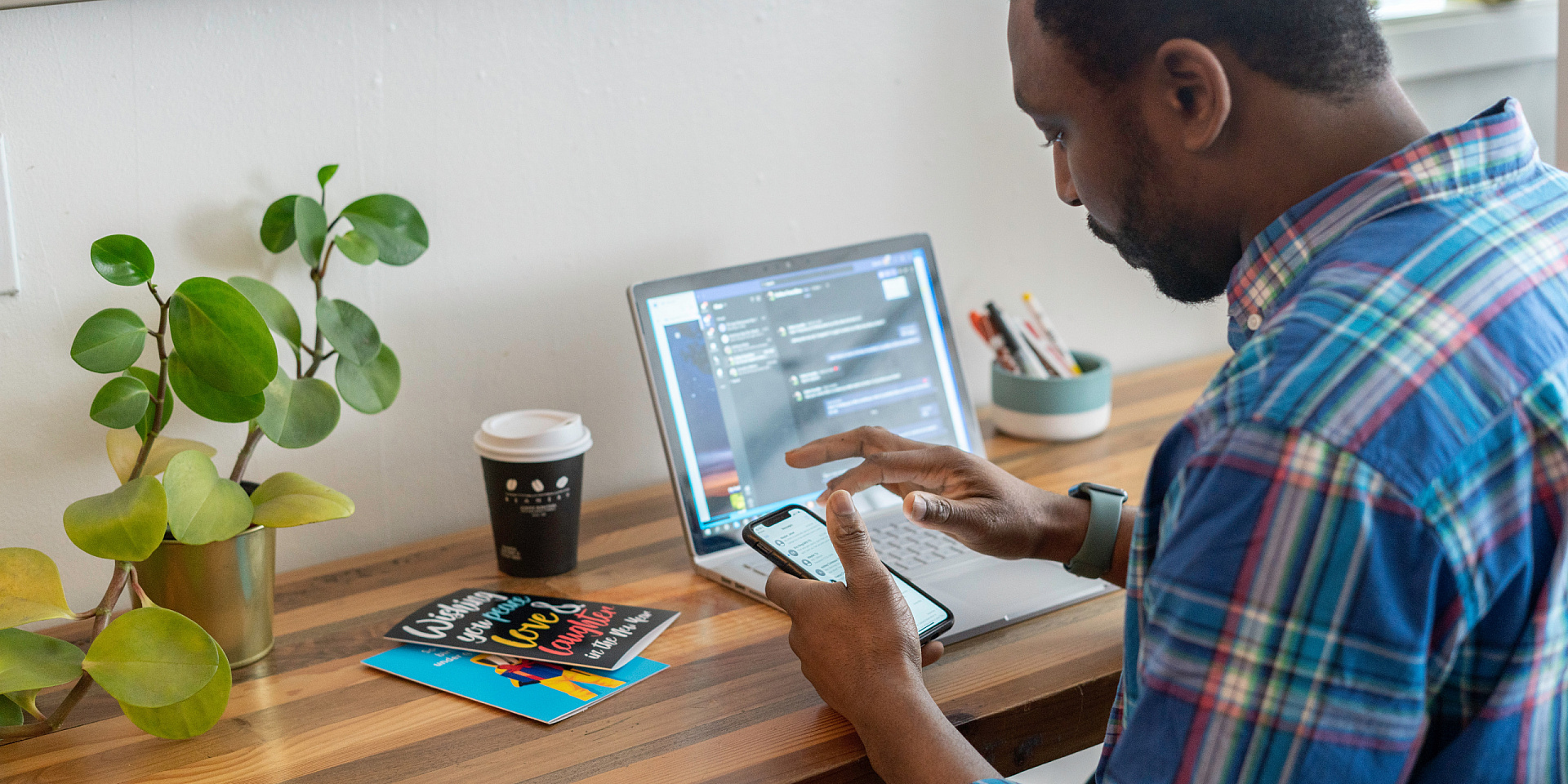 Homme portant une chemise utilise son téléphone à son bureau.