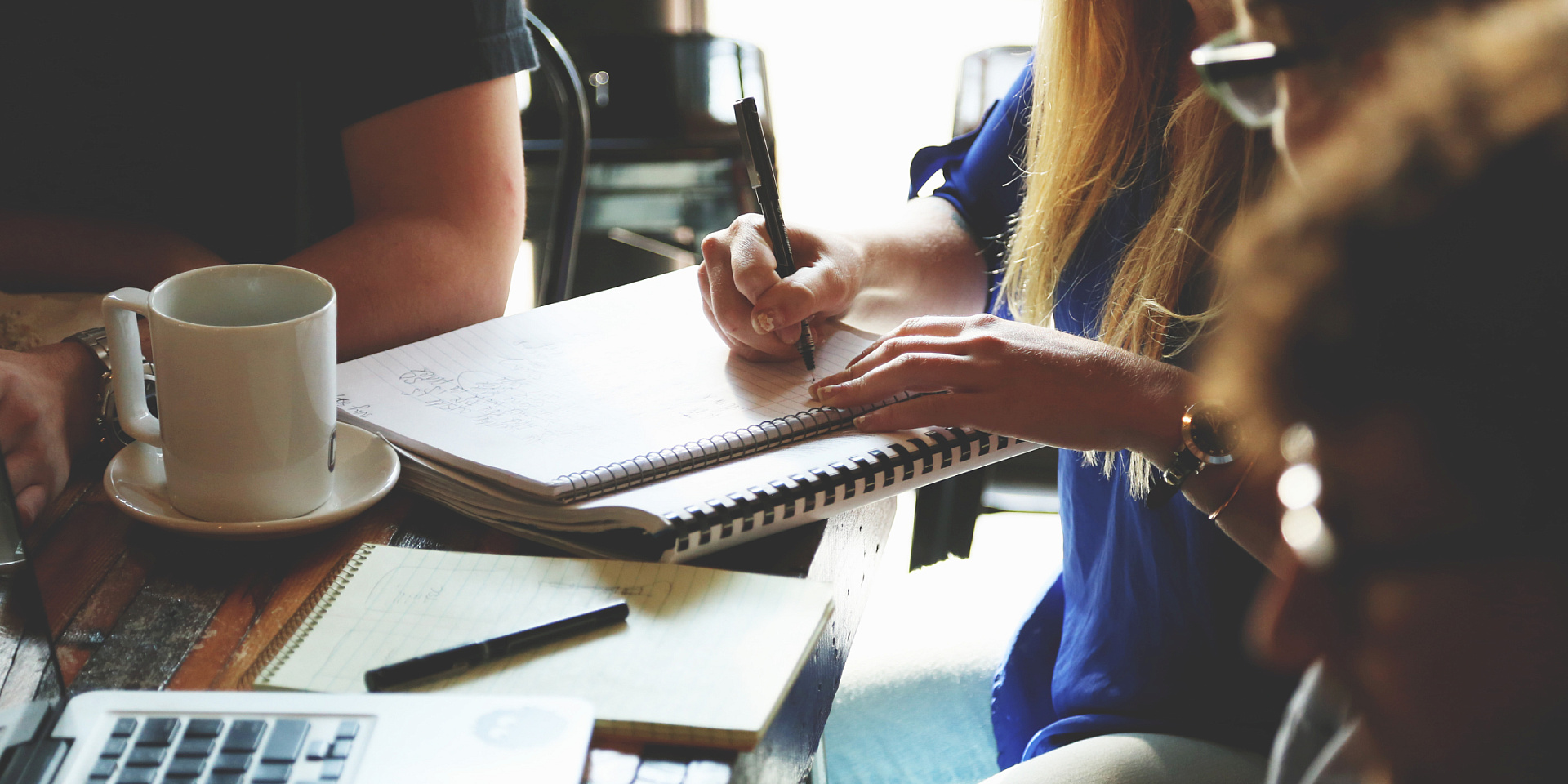 People at a cafe, writing on notebooks.