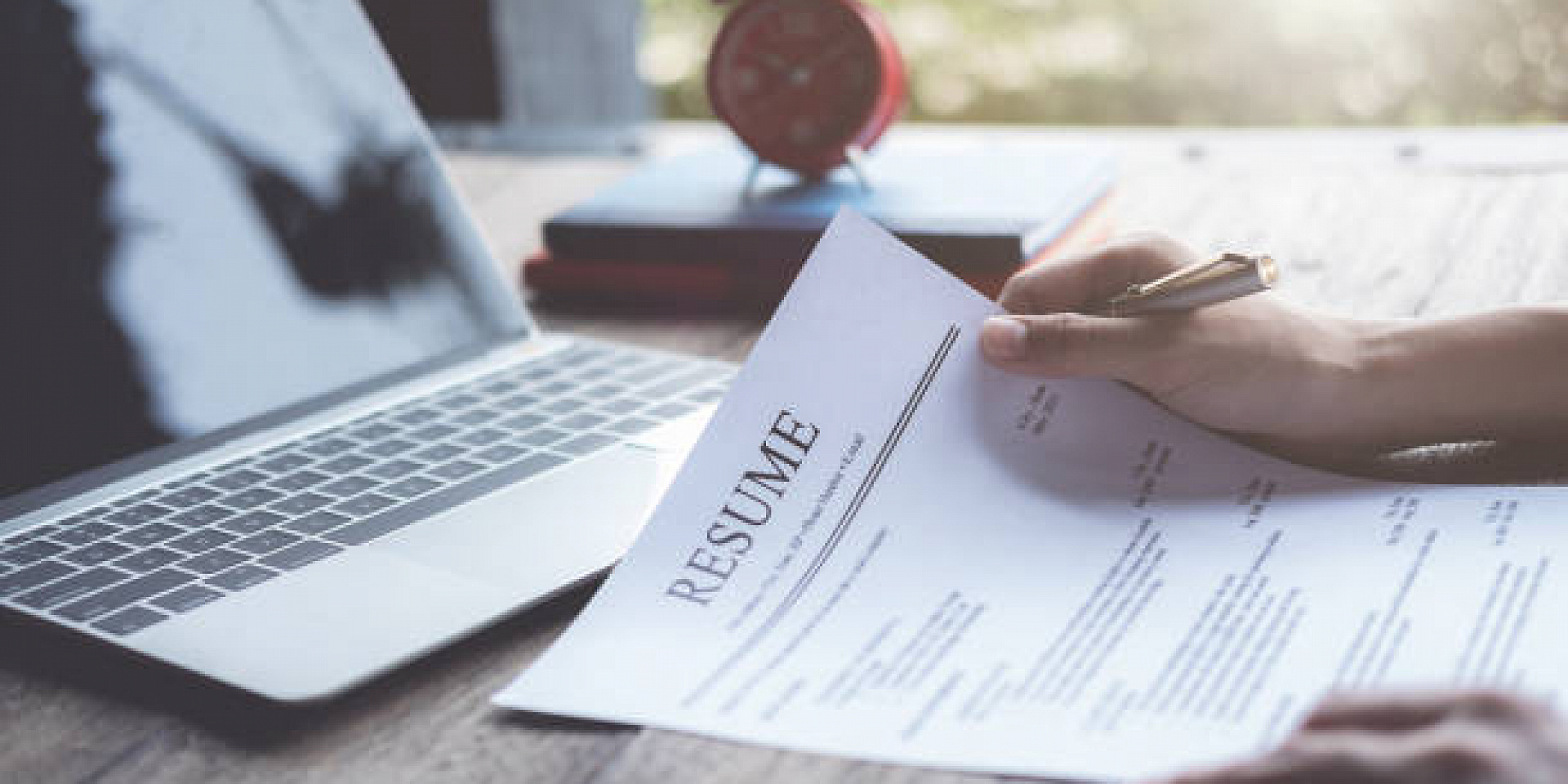 CV sur une table devant un ordinateur portable.