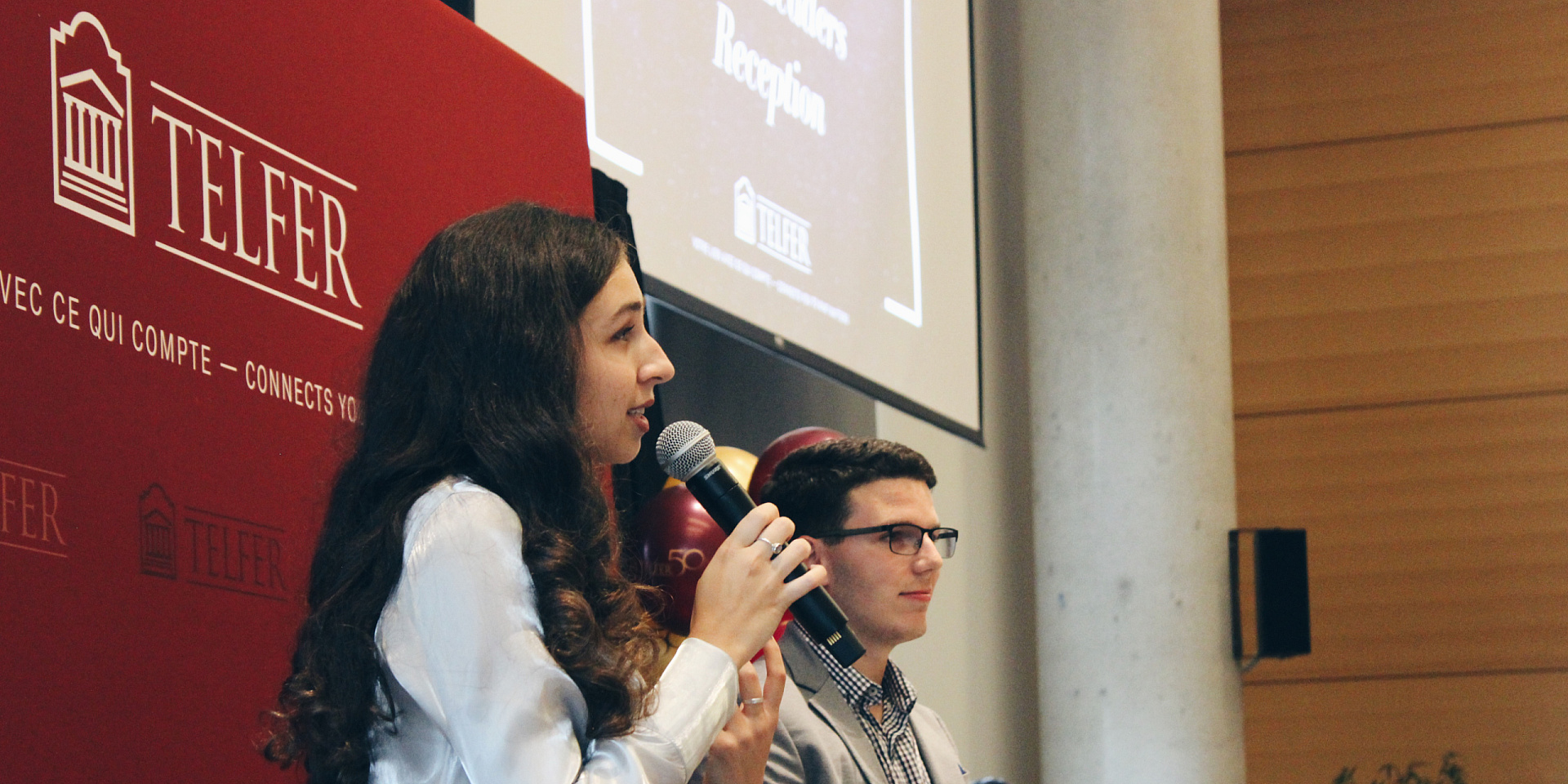 Young woman speaking in a microphone on stage in front of an audience