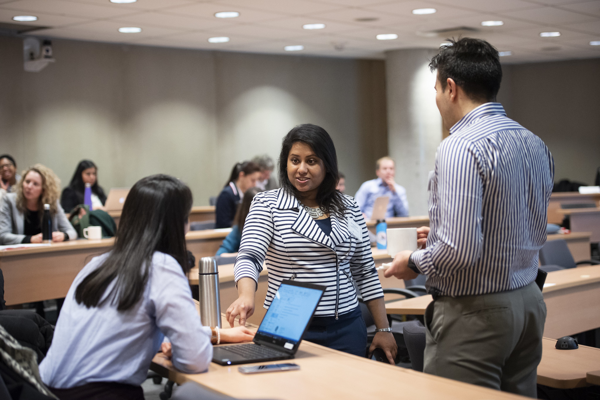 Student asking a question to a professor in a lecture hall.