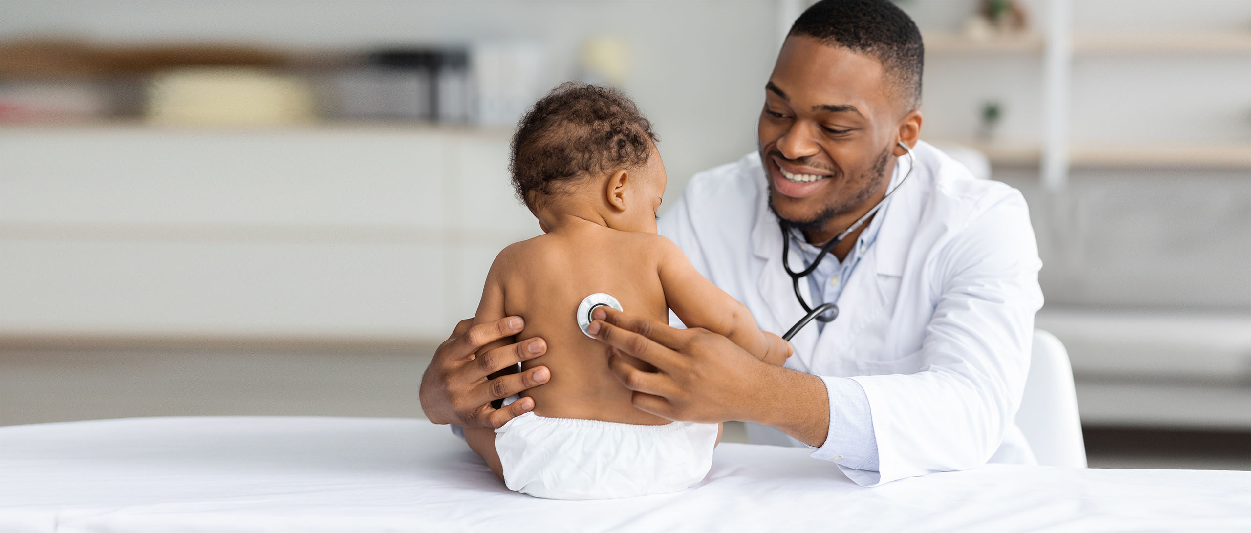Portrait Of Handsome Black Pediatrician Examining Baby Patient With Stethoscope