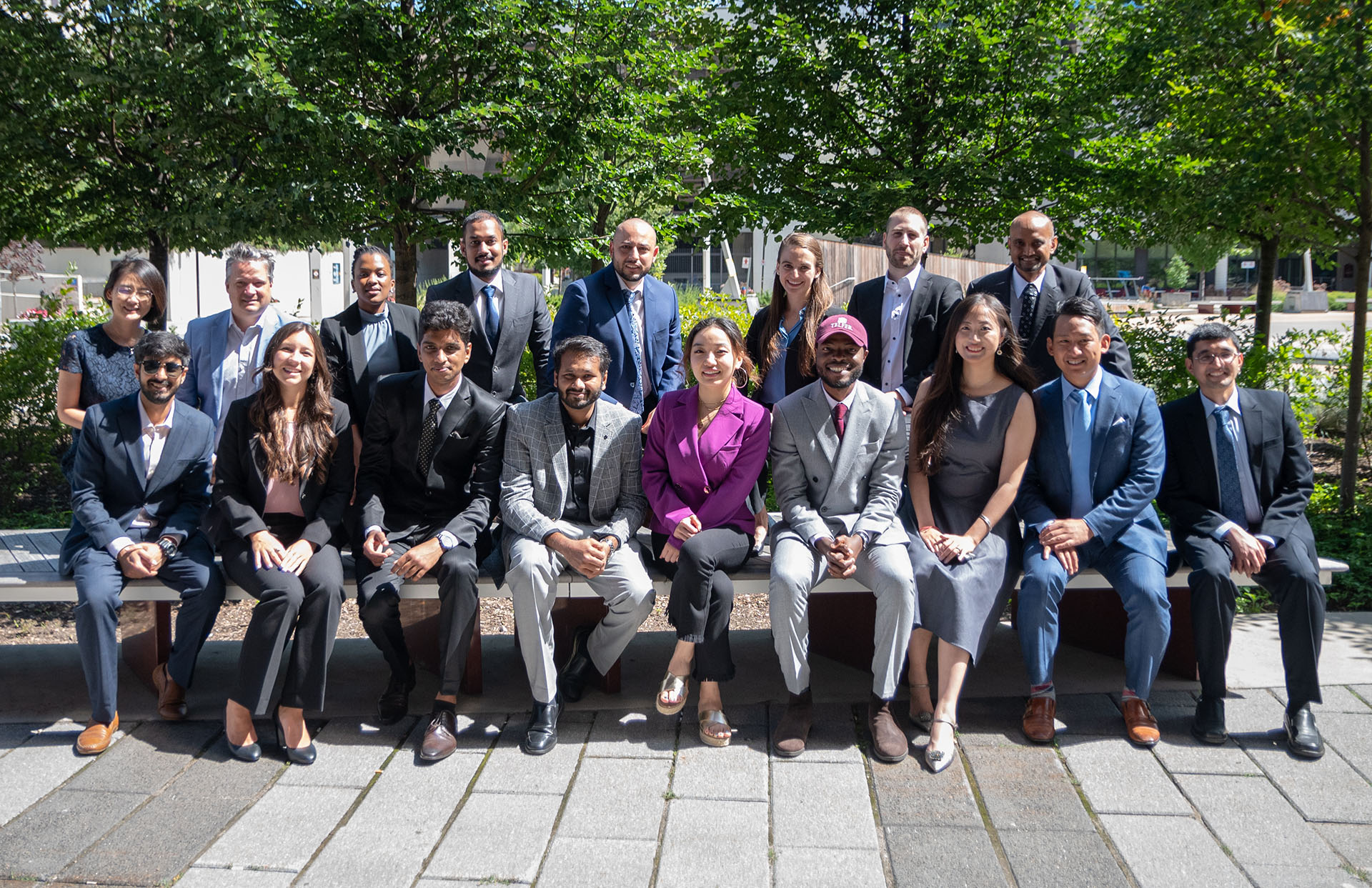 A group of Telfer alumni posing outside on a sunny day.