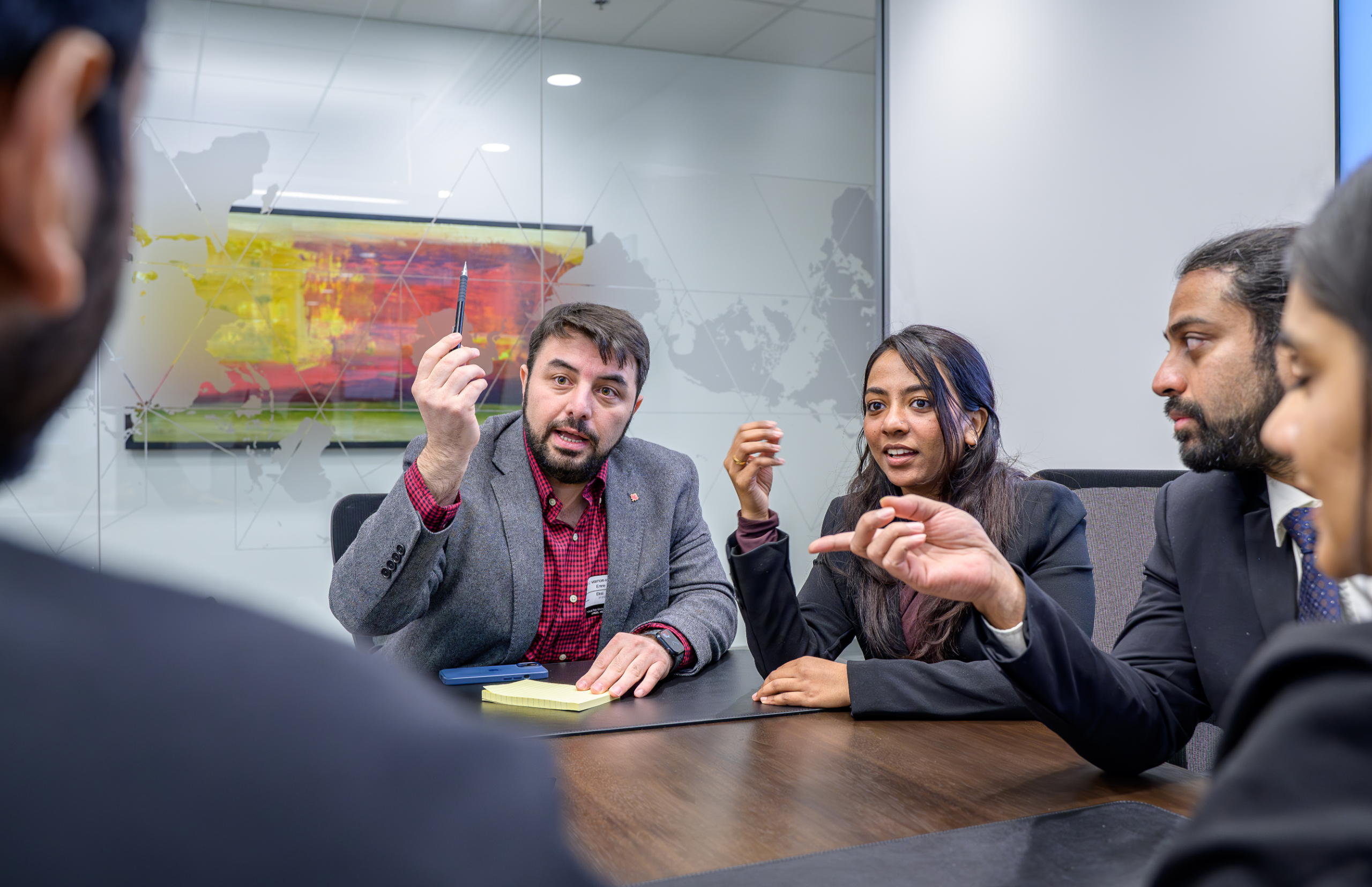 A man and a woman in a conference room actively discuss a case in a group.  