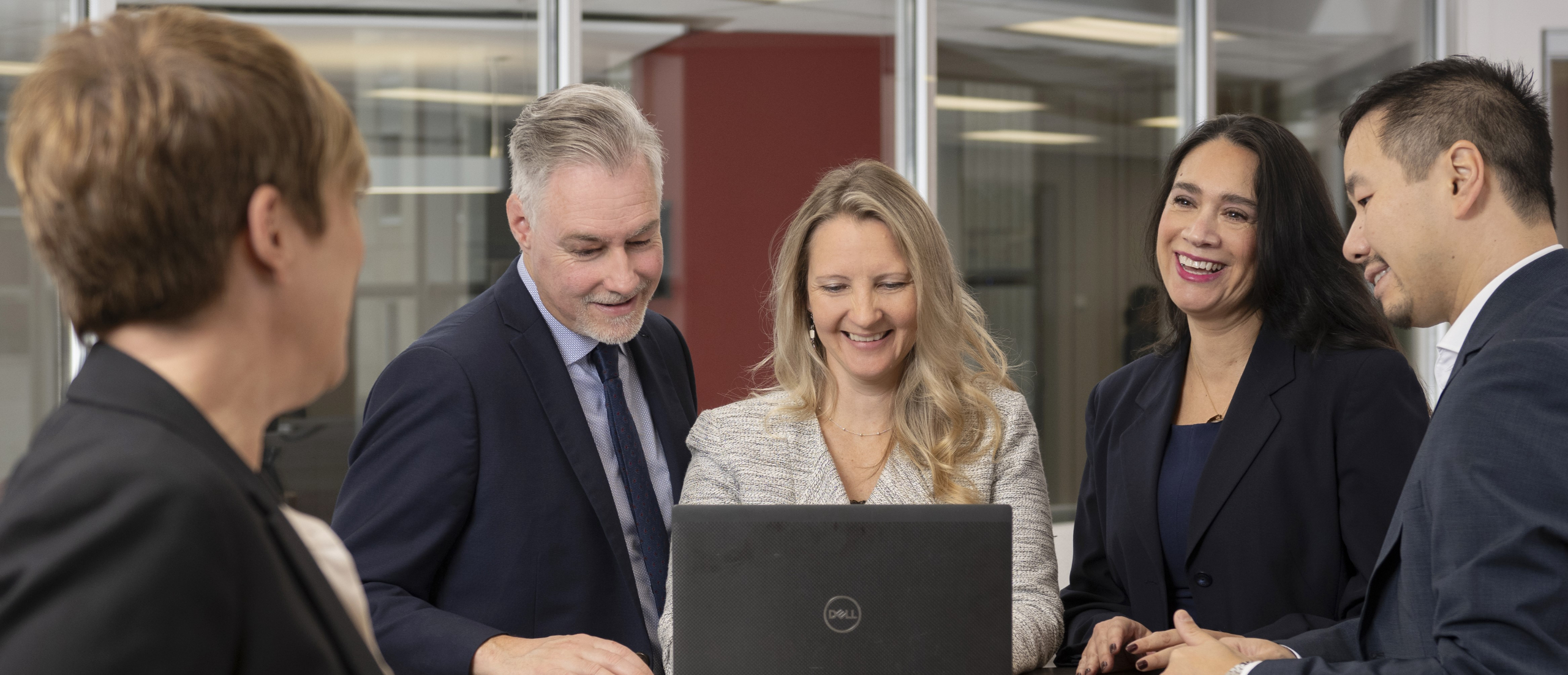 Original photo of Jennifer Hyland, EMBA Manager of Alumni Relation, working on a laptop with a group of Telfer EMBA alumni at the Centre for Executive Leadership.